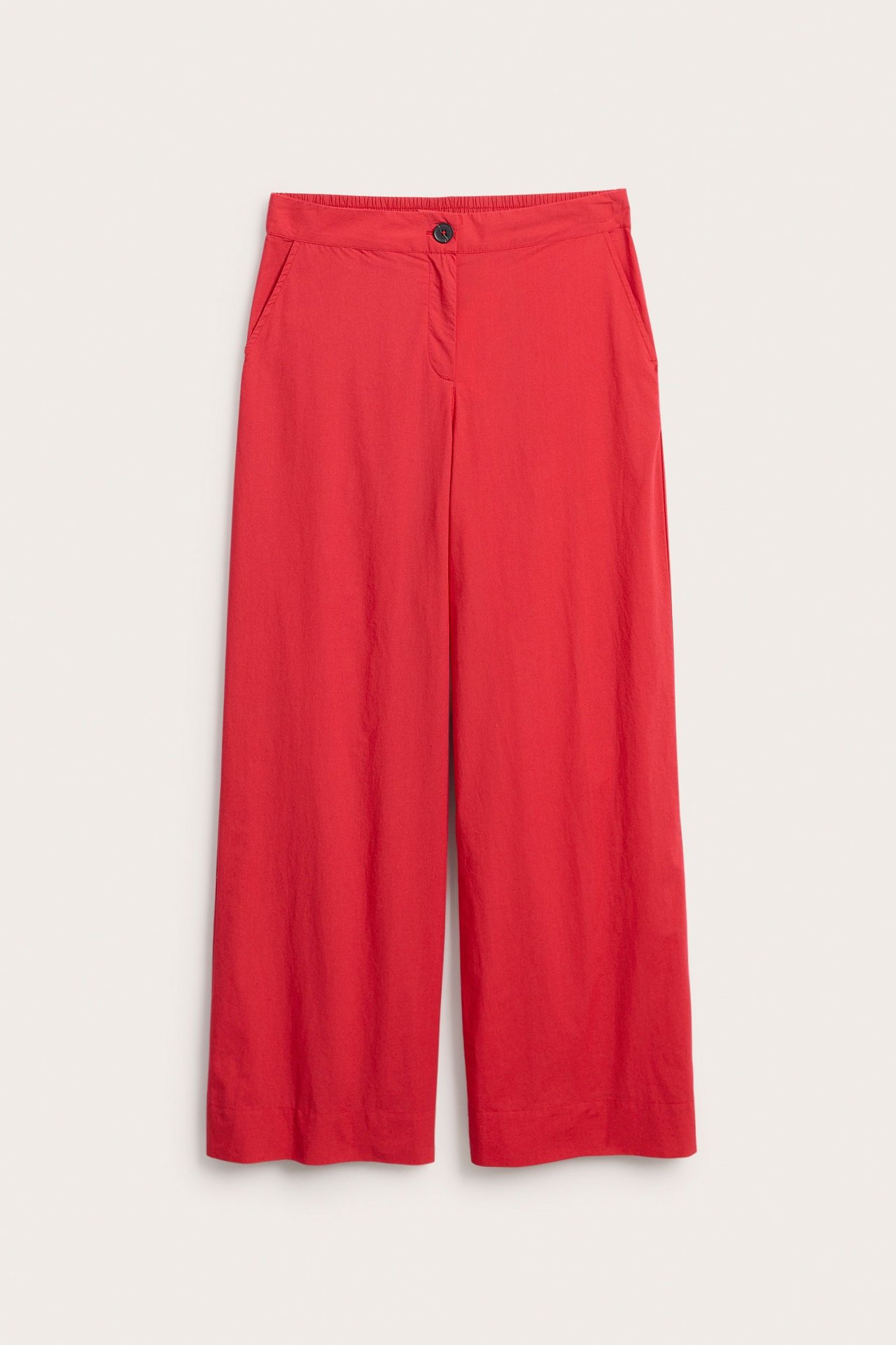 Framifrån: Röda vida bomullsbyxor med gylf, knapp och sidfickor.