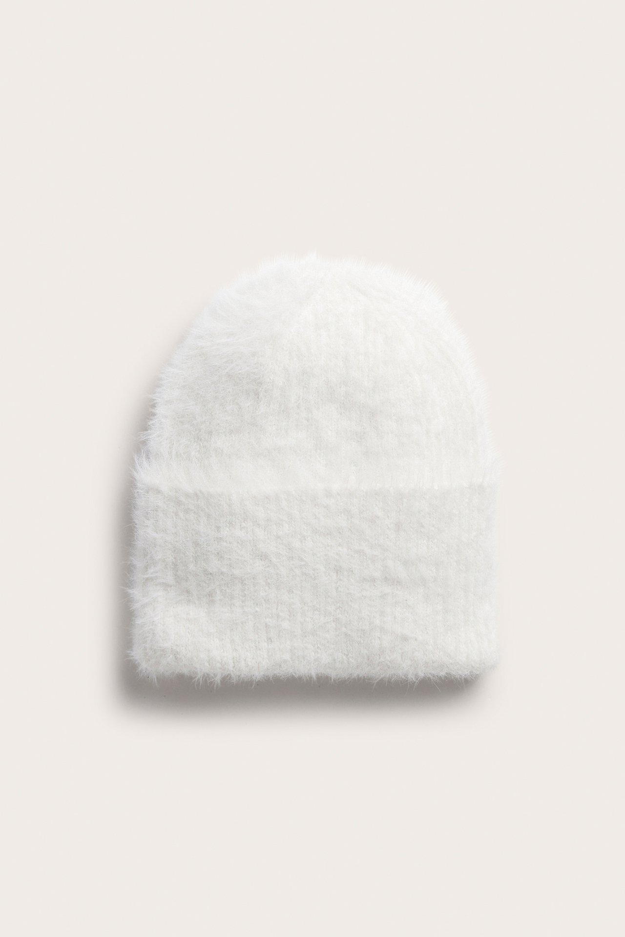 Forfra, hvit fluffy strikket lue med brettet kant.