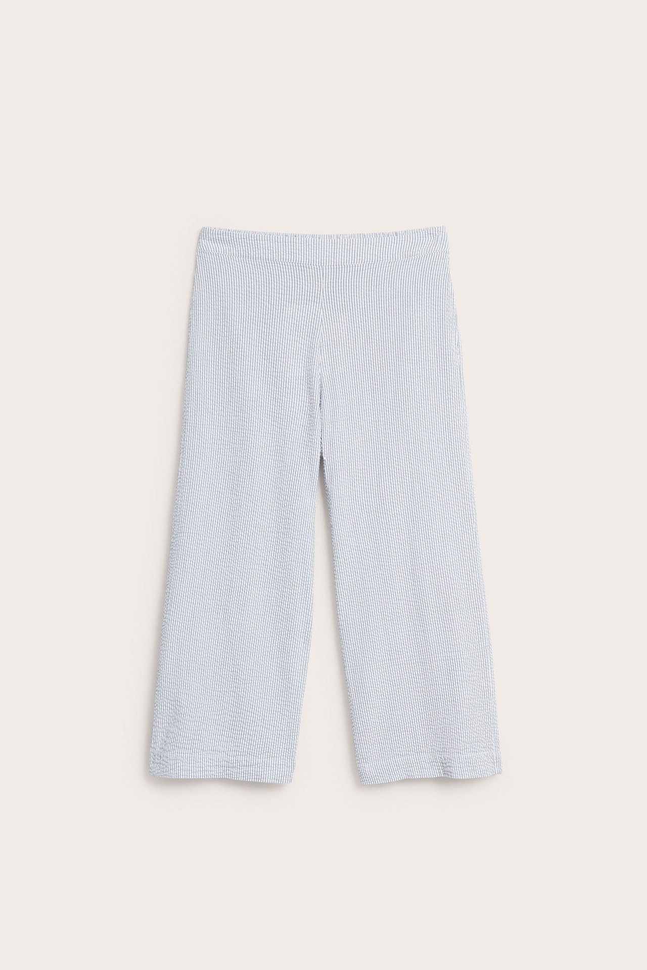 Framifrån: vida, ljusblå och vitrandiga bäckeböljebyxor för dam med resår i midjan.