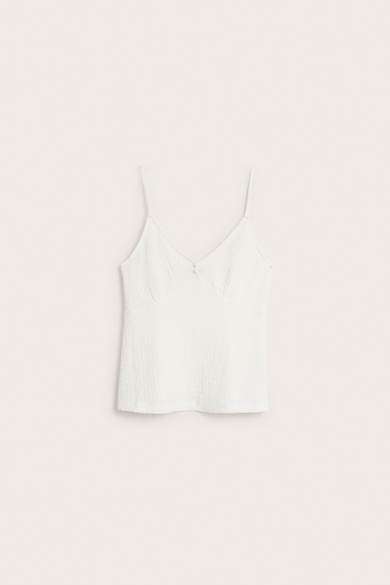 Edestä kuvattu luonnonvalkoinen, strukturoitu toppi ohuilla olkaimilla, V-pääntiellä ja kahdella napilla.