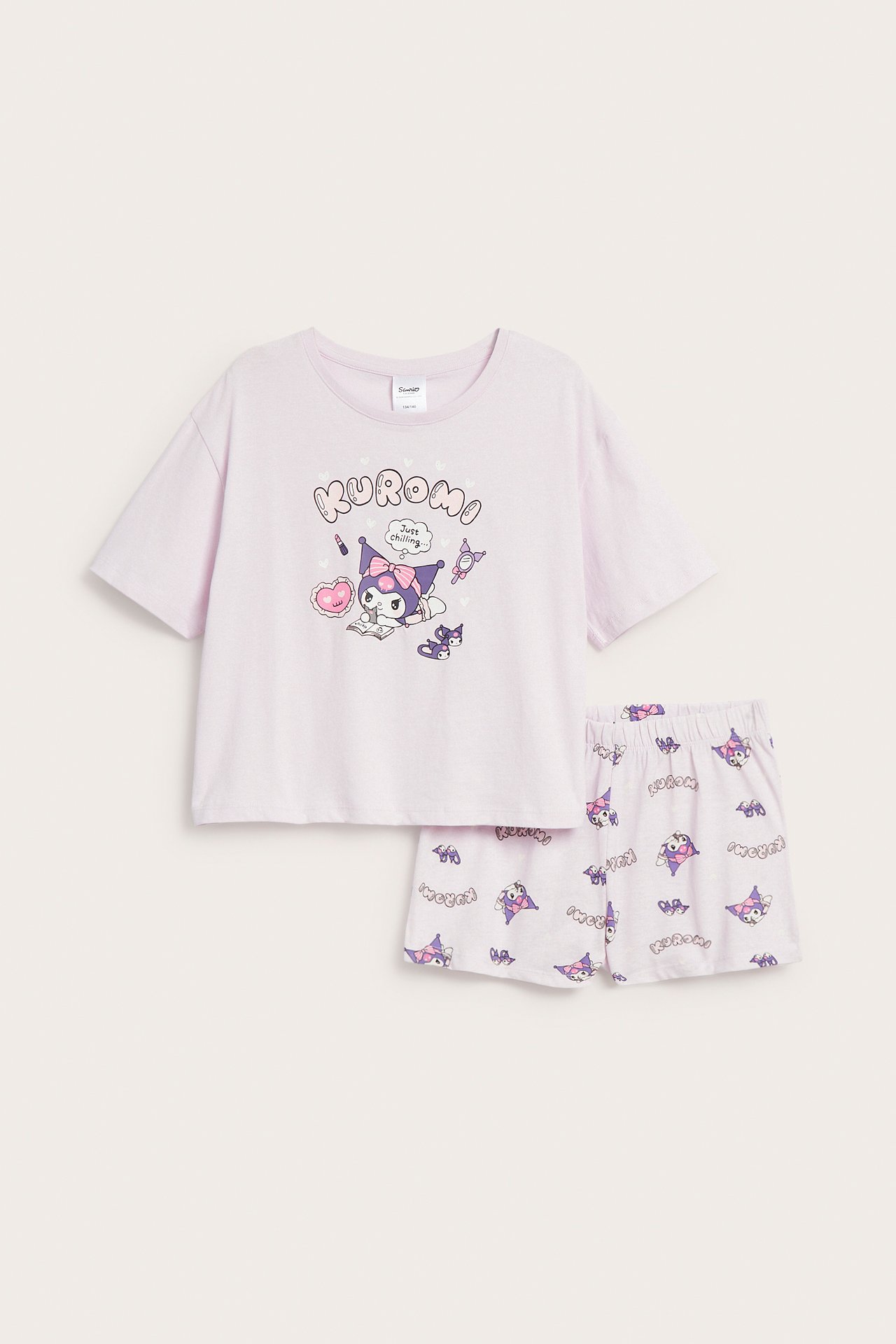 Widok z przodu dziecięcej, liliowej piżamy Kuromi: krótki rękaw z nadrukiem, szorty z nadrukiem na całej powierzchni.