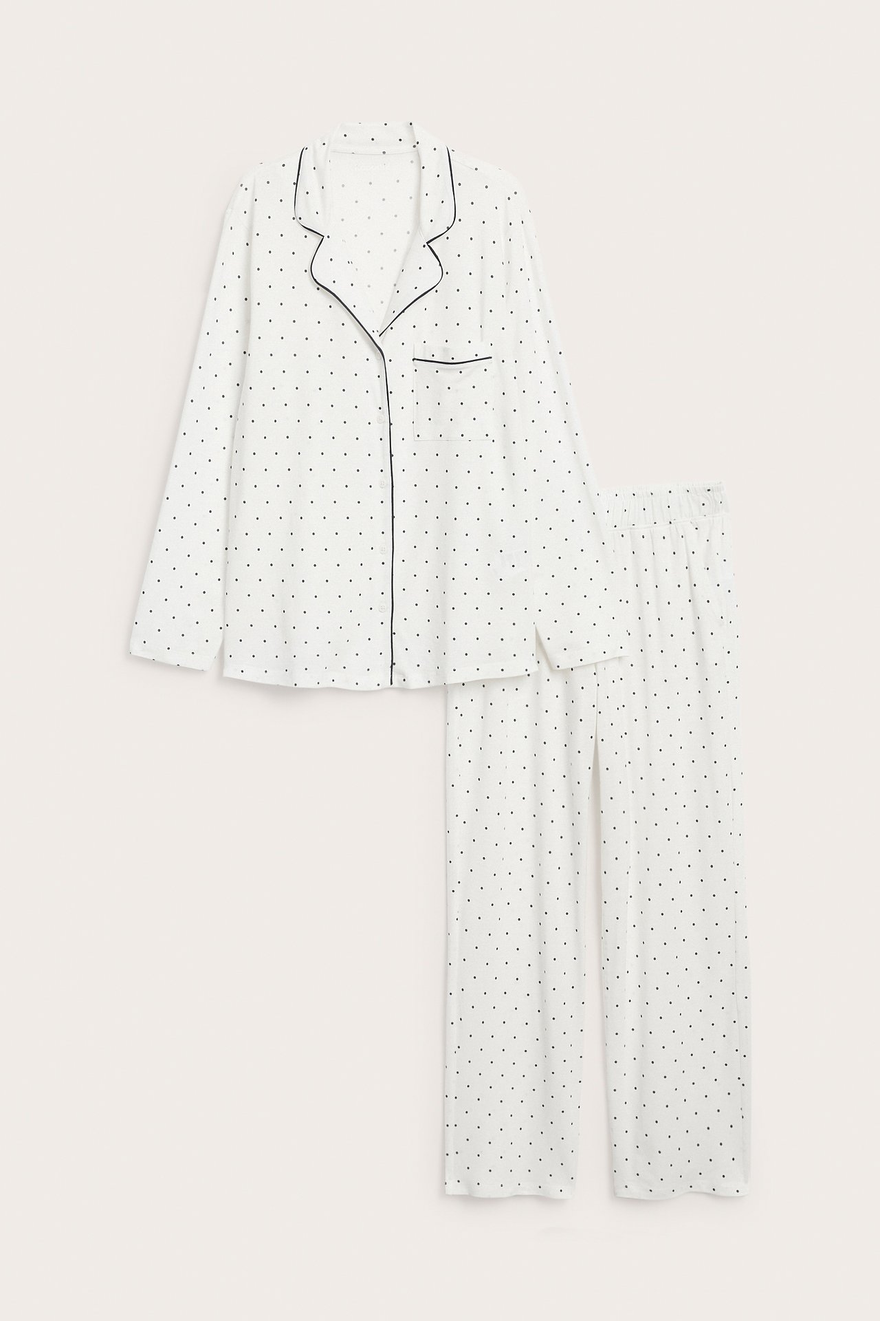 Edestä valkoinen pilkullinen pyjamassetti, jossa pitkähihainen paita ja housut.