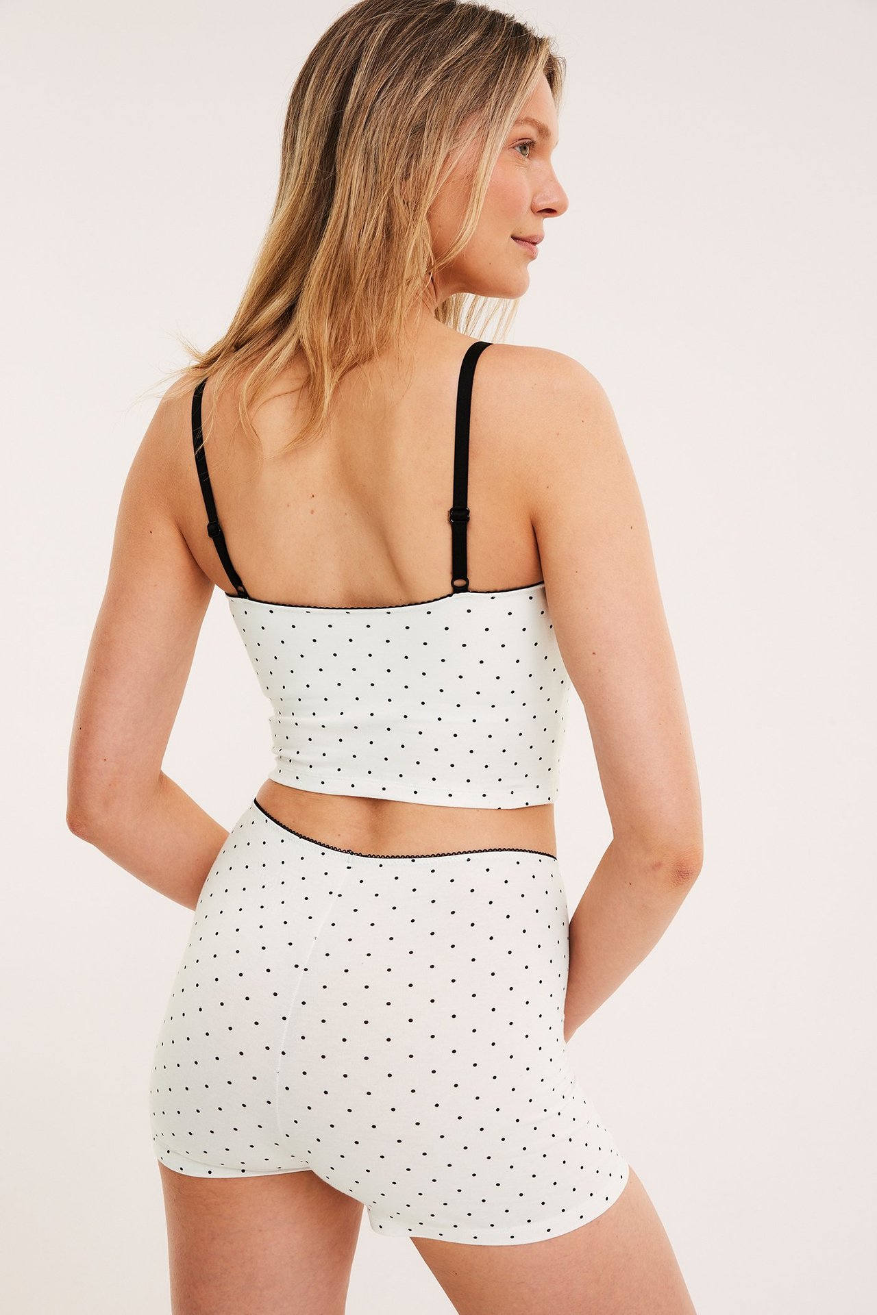 Ryggvy av kvinna i offwhite prickiga bomullsshorts med picotkant och matchande camisole.