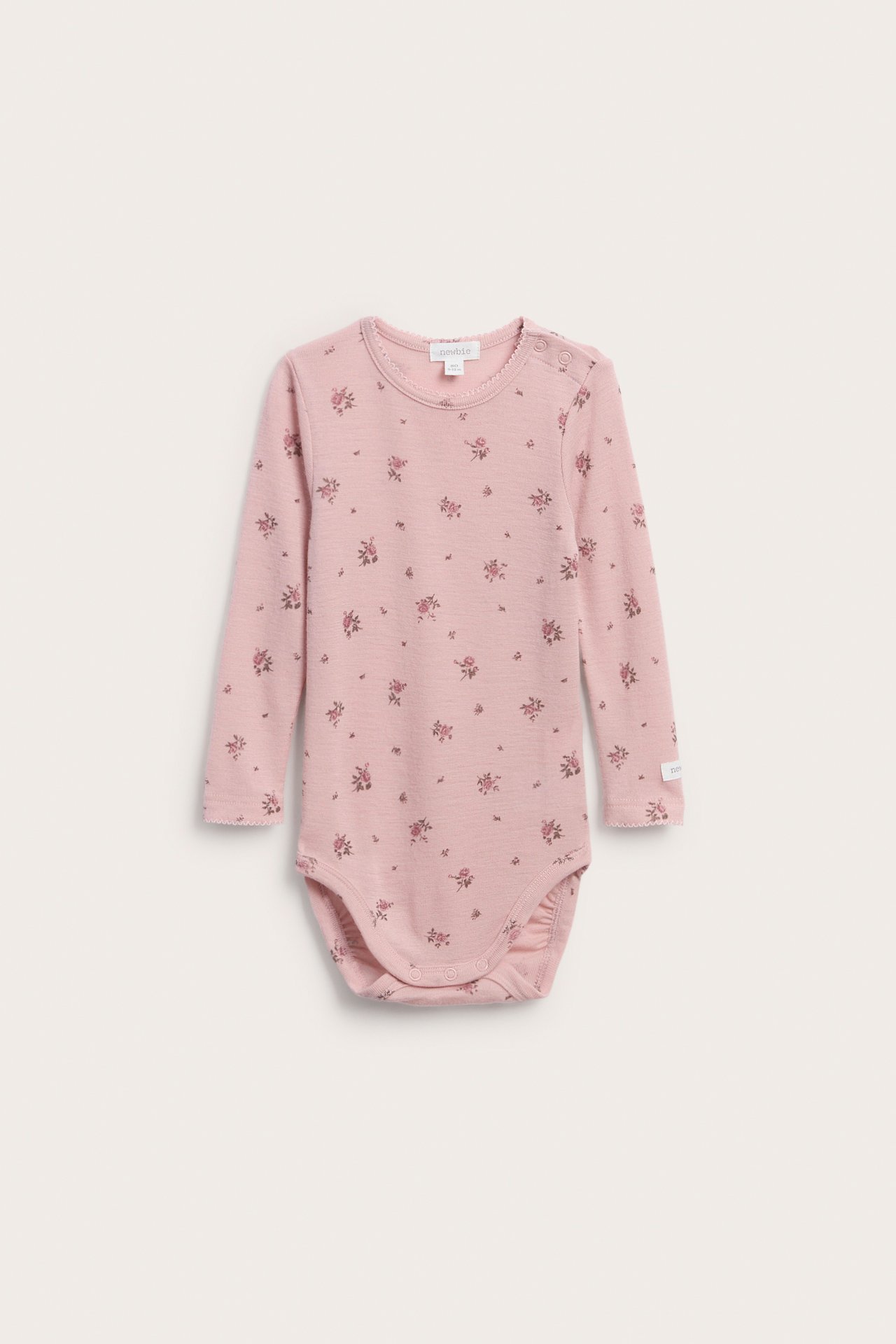 Forfra en rosa langermet babybody med blomstermønster og trykknapper.