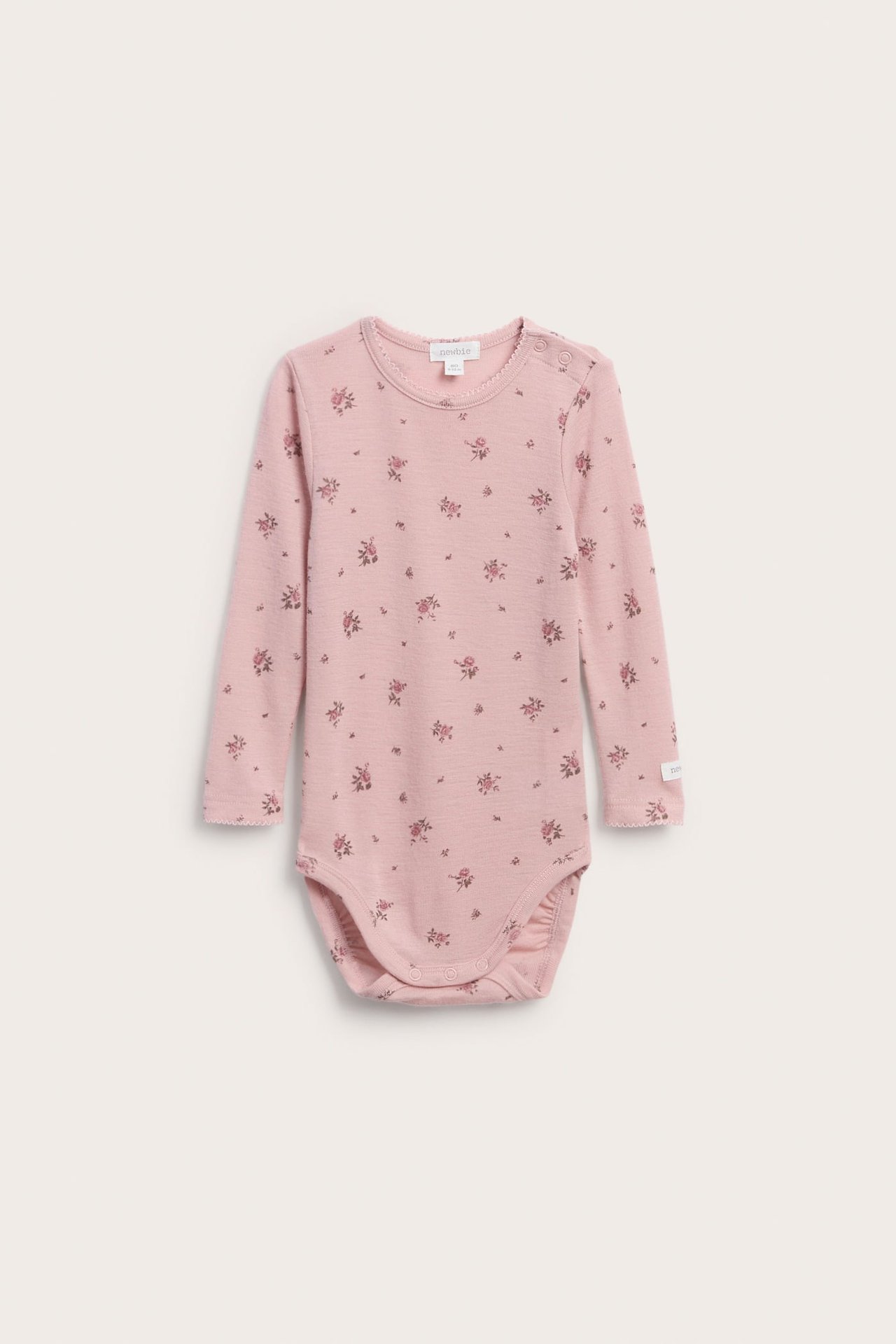Framifrån en rosa långärmad babybody med blommönster och tryckknappar.