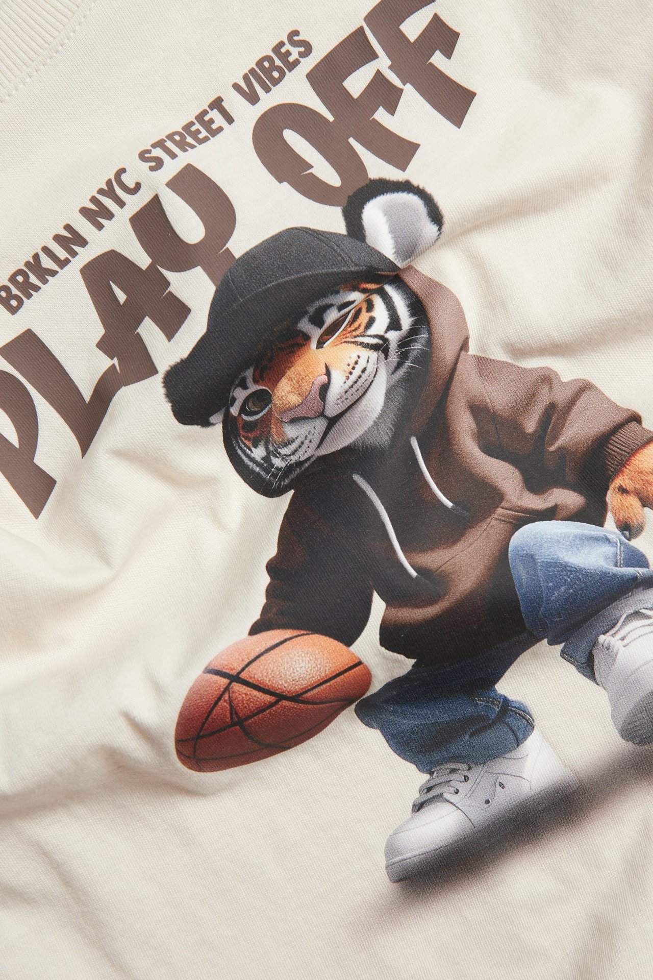 Widok z przodu: Jasnobeżowy bawełniany T-shirt oversize z nadrukiem tygrysa w bluzie, trzymającego piłkę.