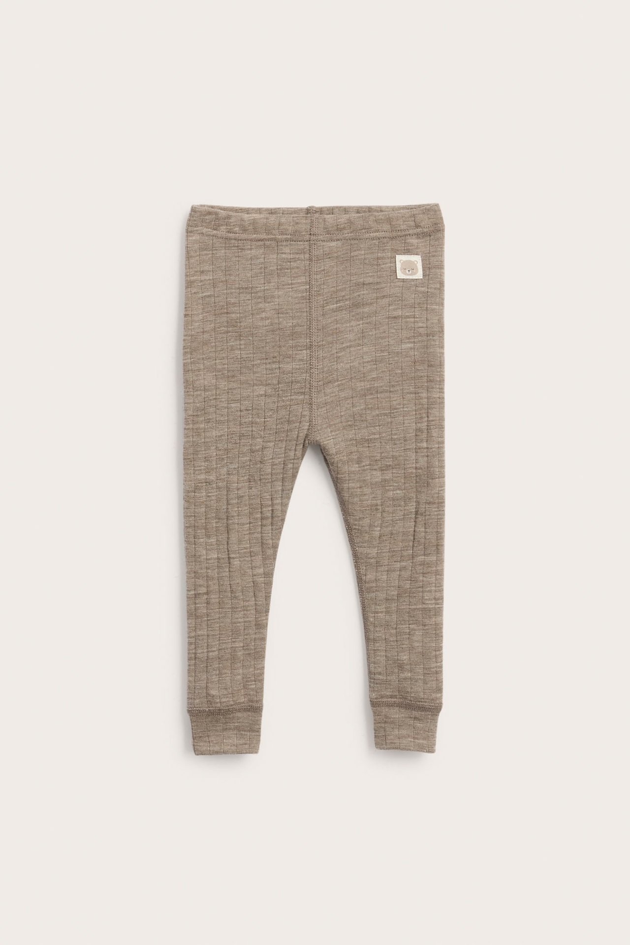 Framifrån ribbade bruna baby-leggings med liten etikett.