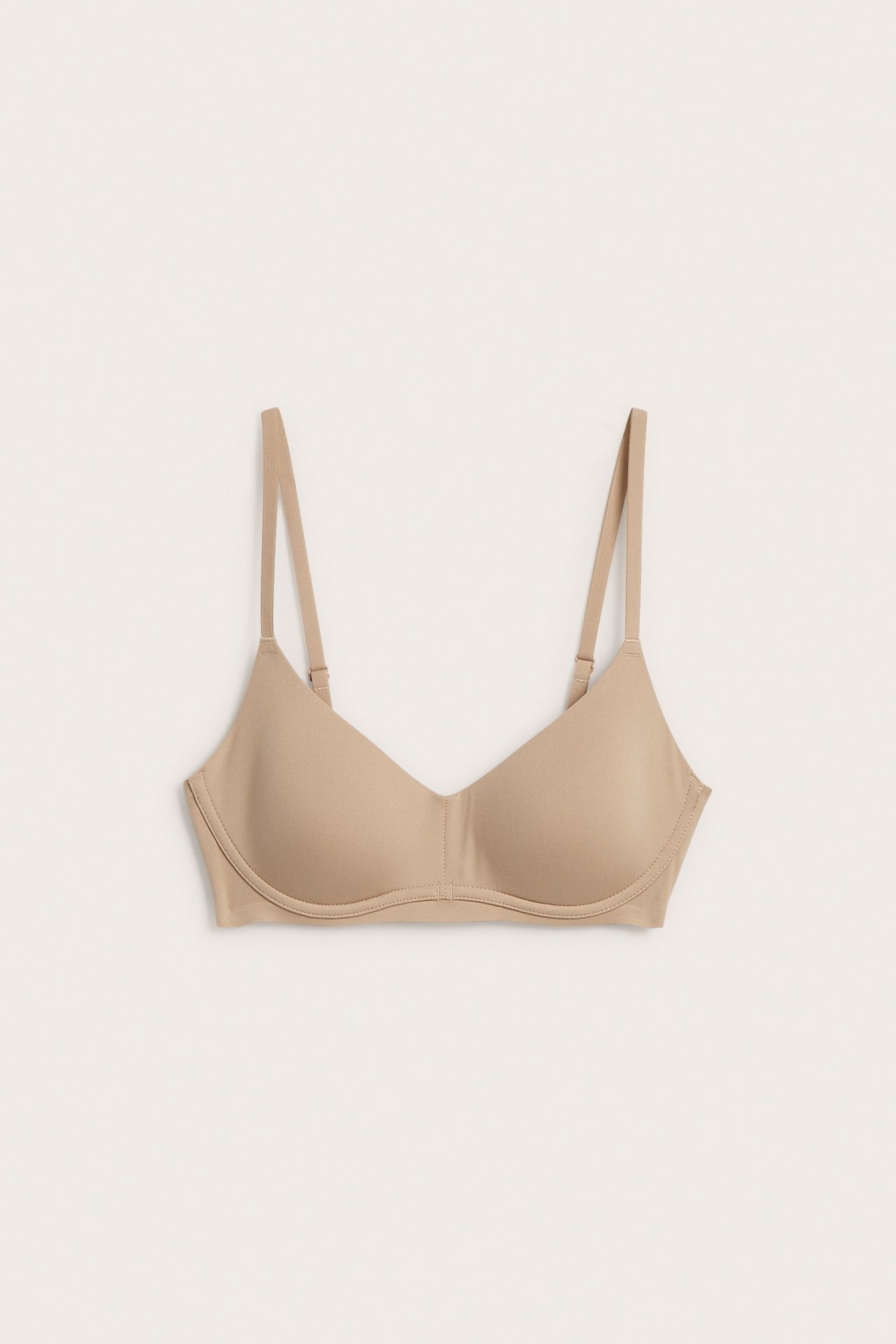 Edestä, yksinkertainen beige rintaliivi säädettävillä olkaimilla.