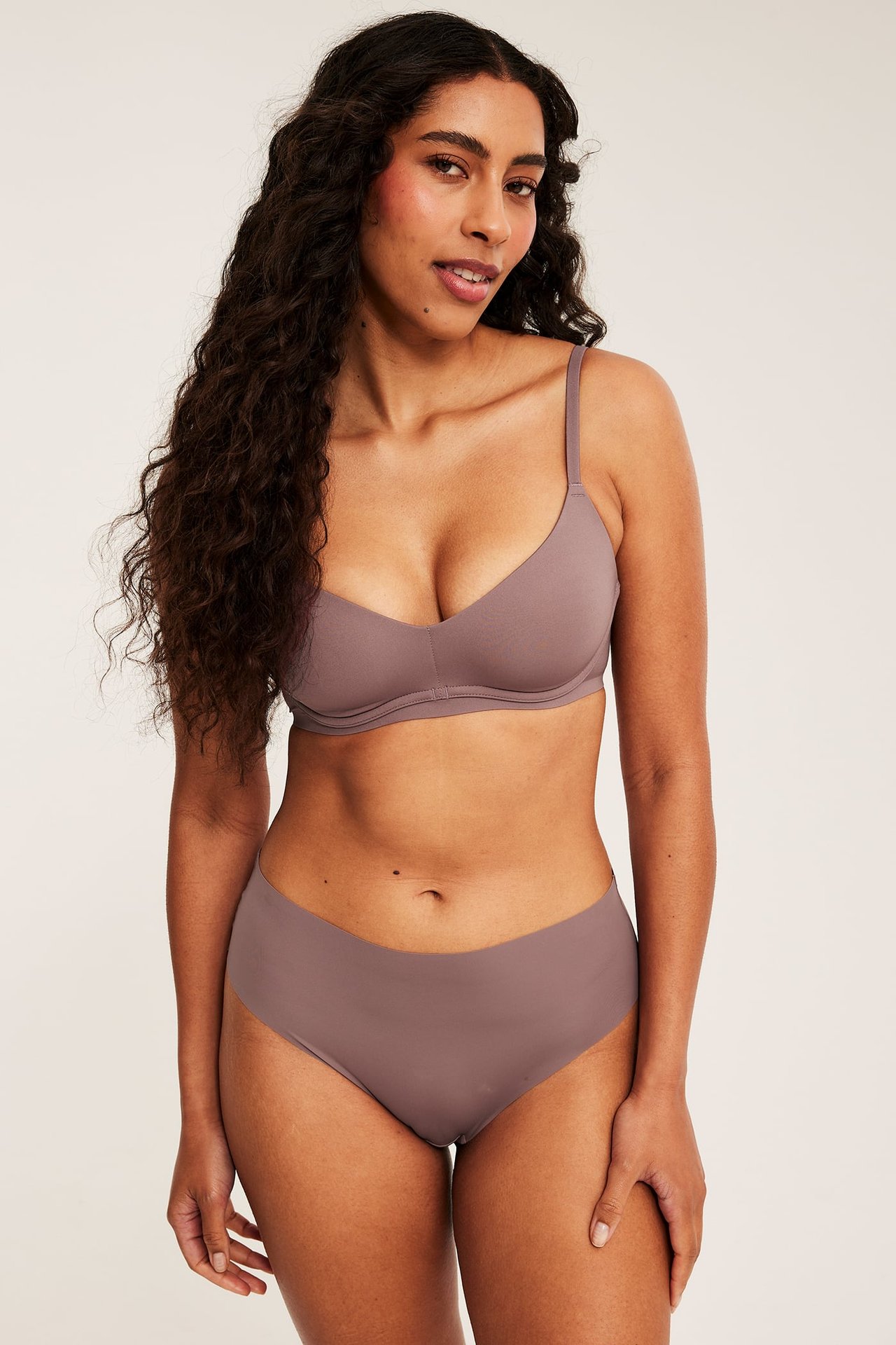 Frontbilde av kvinnelig modell i sømløs mauve bh og matchende truse.