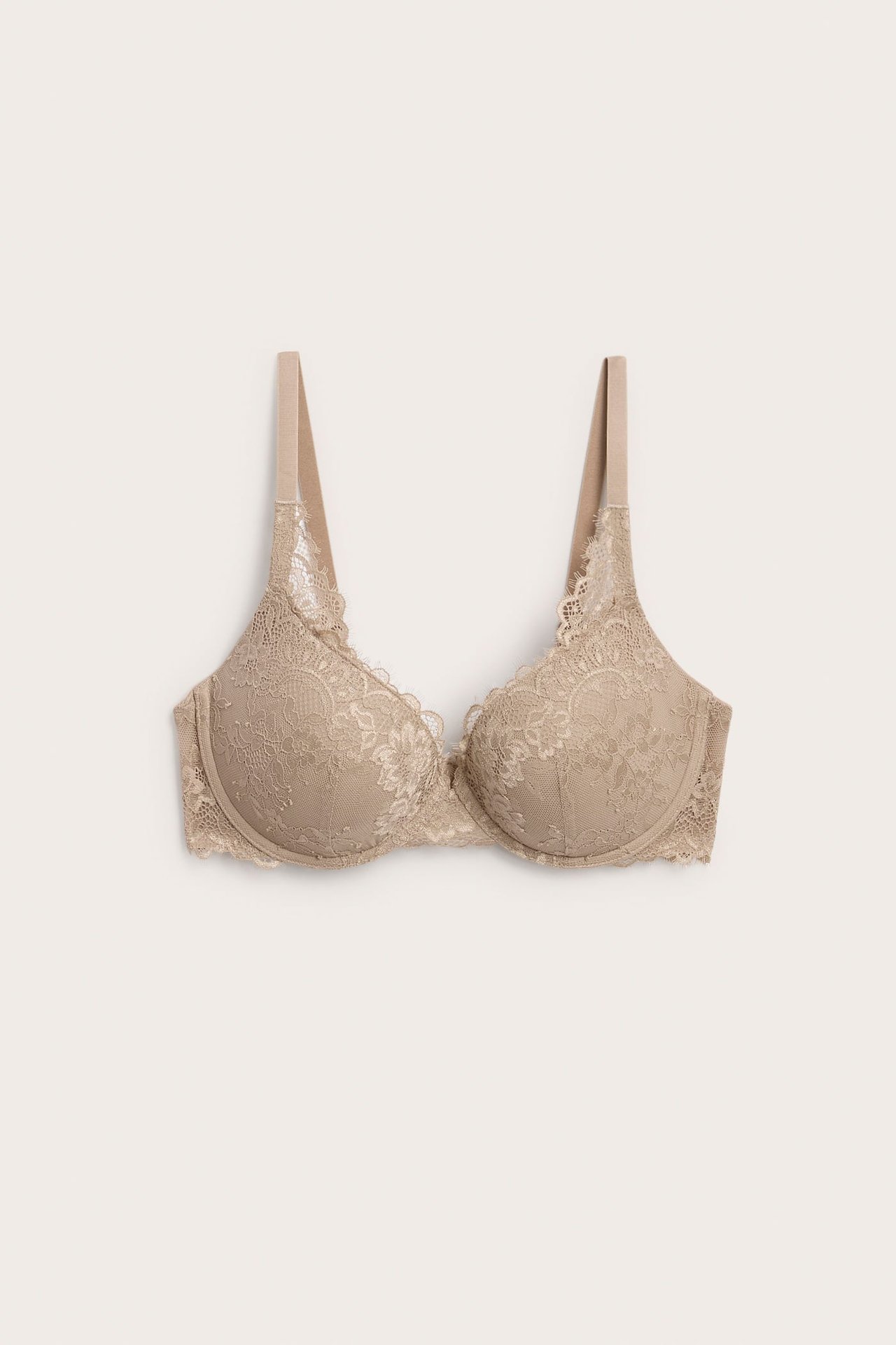 Edestäpäin kuvattu beige pitsinen push-up rintaliivit herkällä kukkakuviolla.