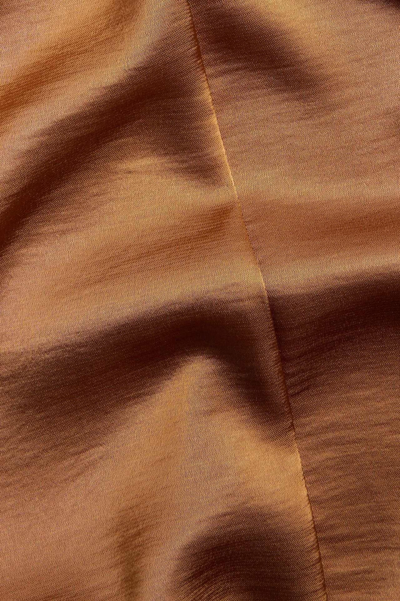 Nærbilde av beige satengstoff med subtil glans og myke folder.