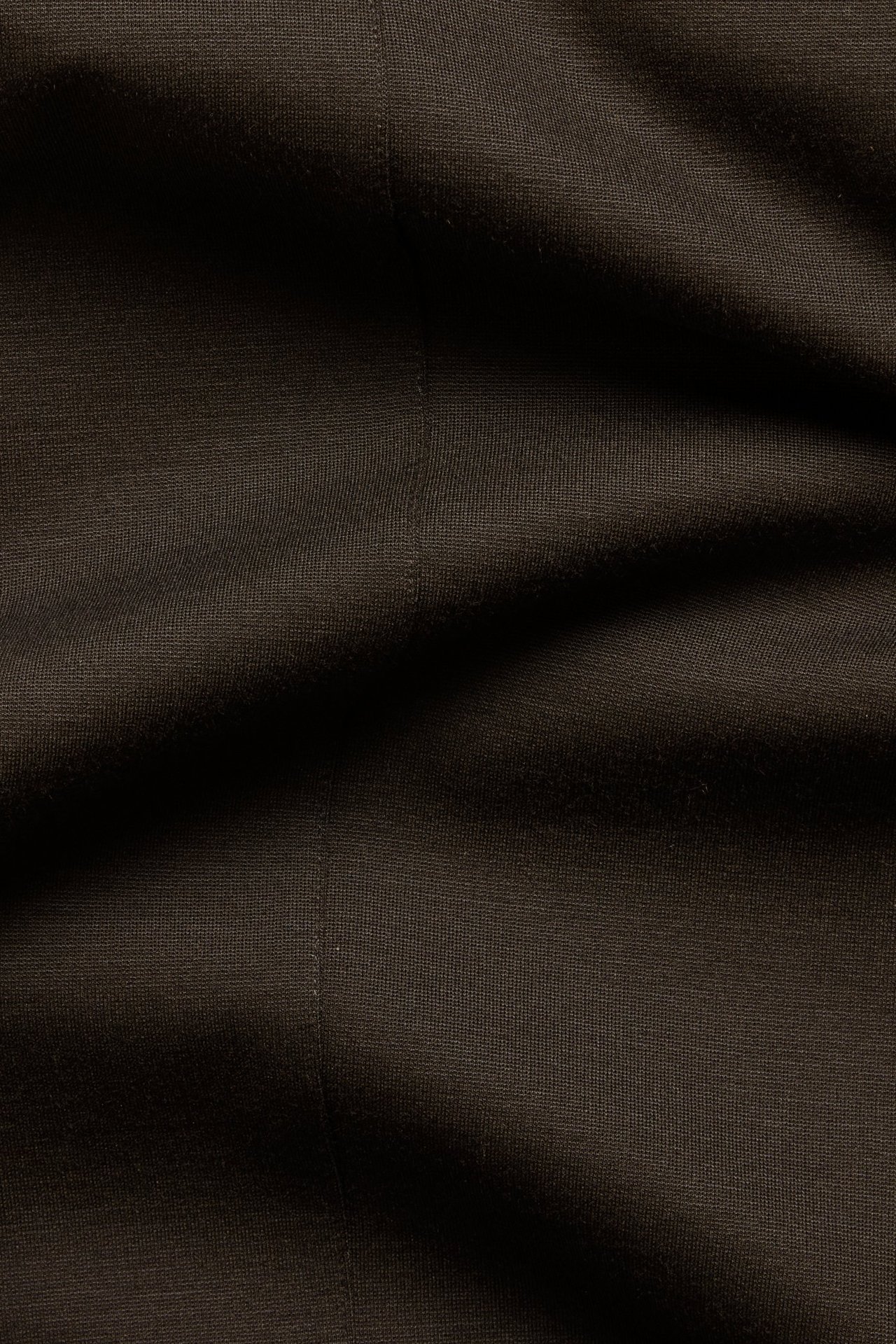 Lähikuva tummanruskeasta Punti di Roma -kankaasta suoriin vetohousuihin, edessä sauma.