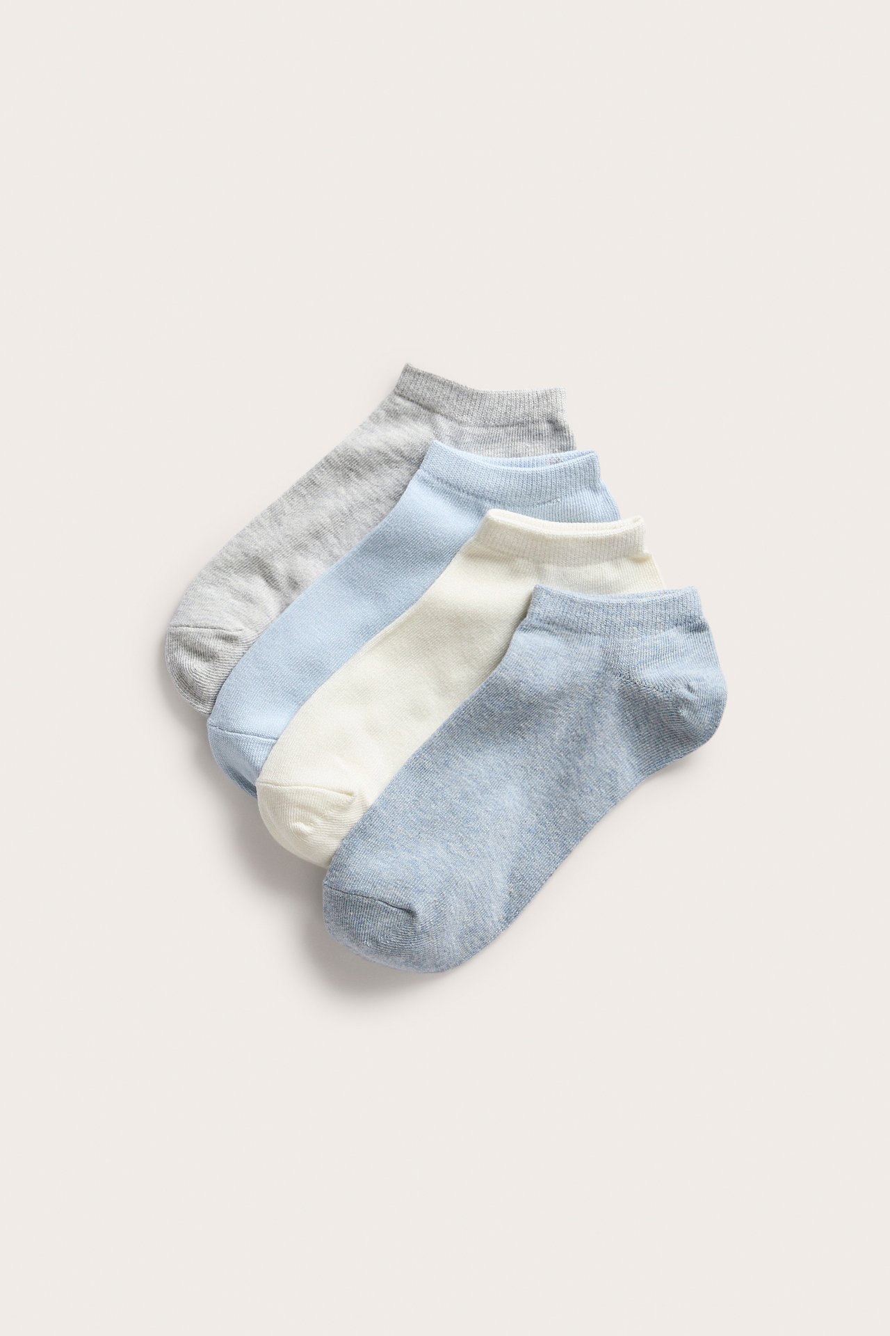 Uppifrån sett fyra par melerade sneakersstrumpor i ljusblått, ljusgrått och benvitt.