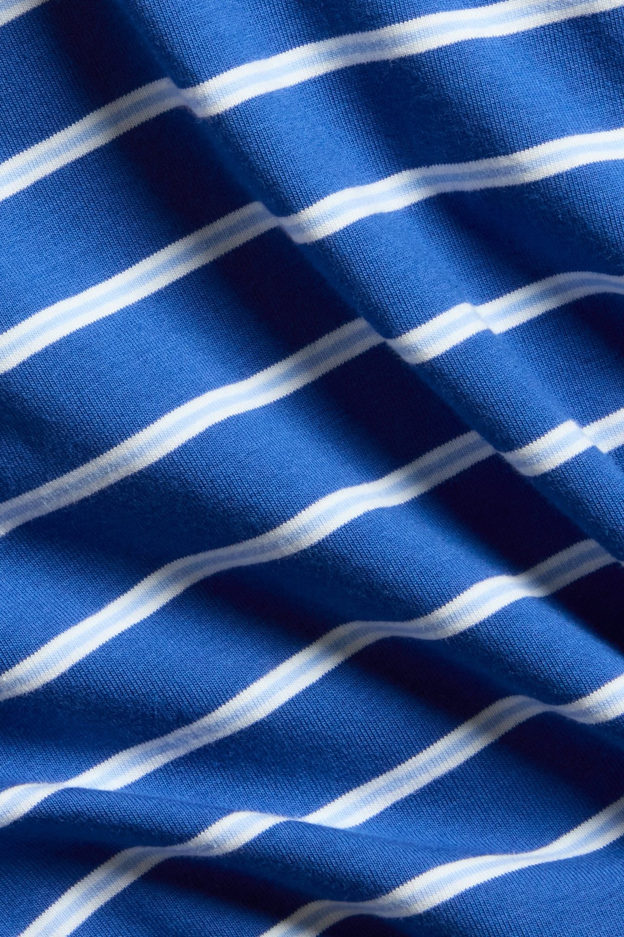 Zbliżenie na niebieską tkaninę t-shirtu z białymi i jasnoniebieskimi paskami.