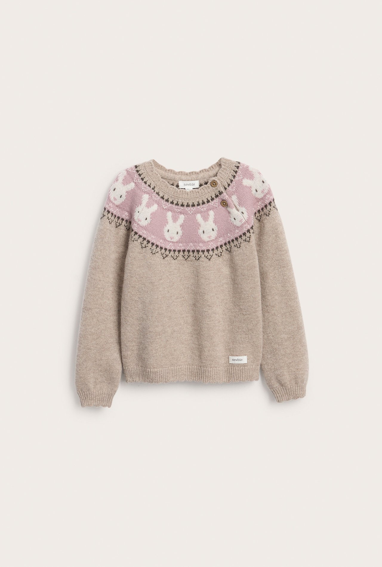 Forfra, beige barnegenser med rosa bærestykke, hvitt kaninmønster og to knapper.