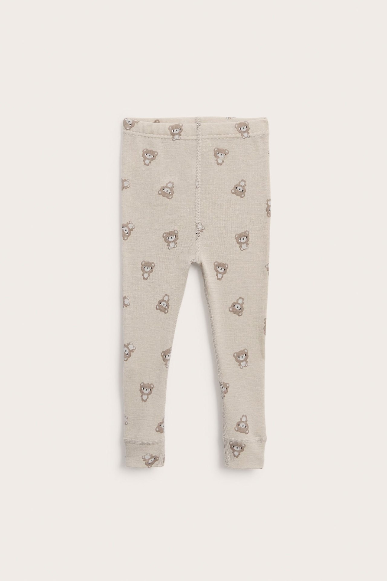 Edestä näkymä vauvan beigeistä slim-fit-leggingseistä nallekuviolla.