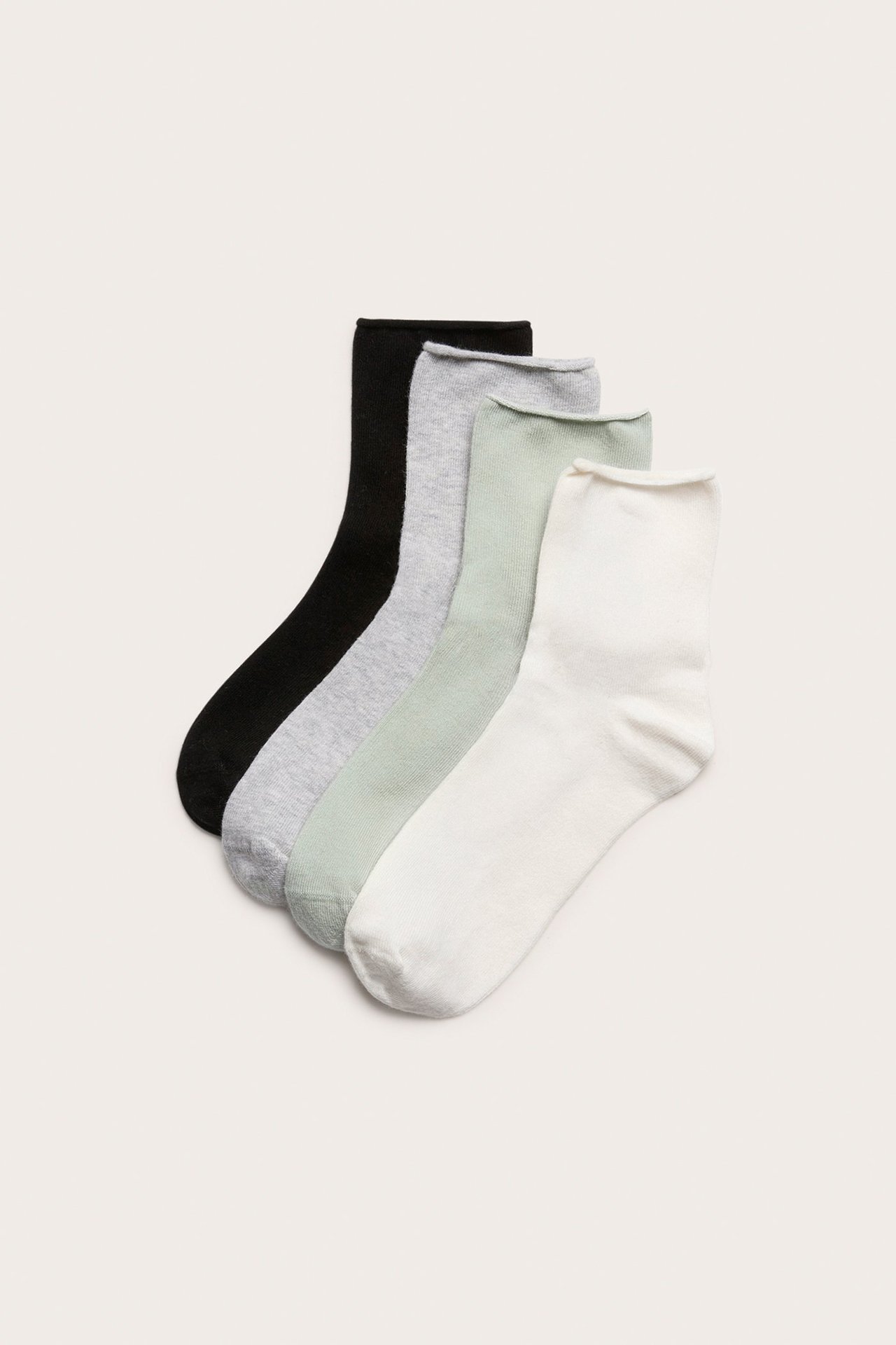 Flat lay-bilde av fire bomullsblandingssokker med rullekant: svart, lysegrå, lysegrønn og off-white.