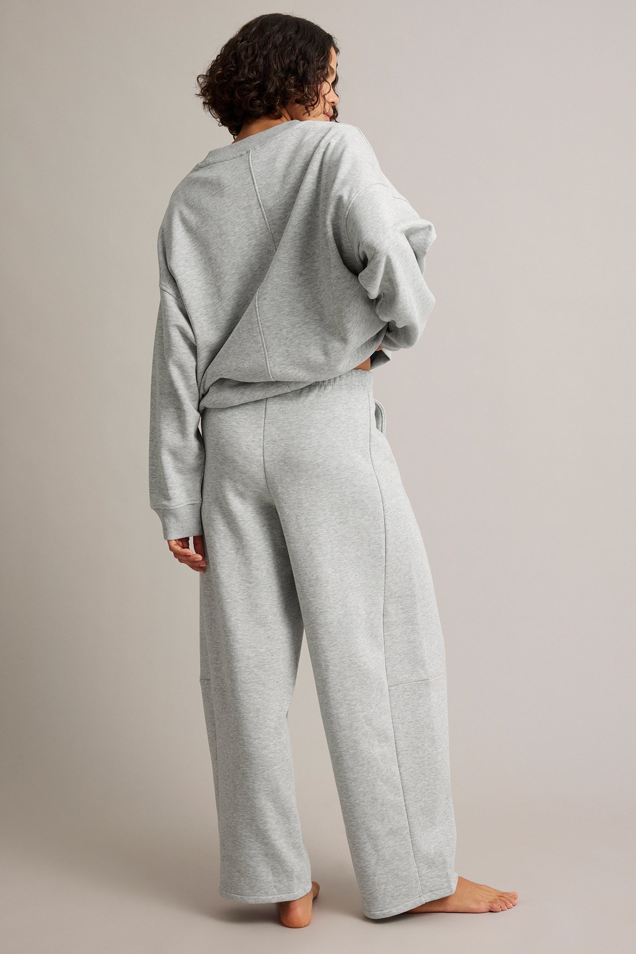 Kvinna sedd bakifrån i en grå oversized sweatshirt och matchande vida sweatpants.