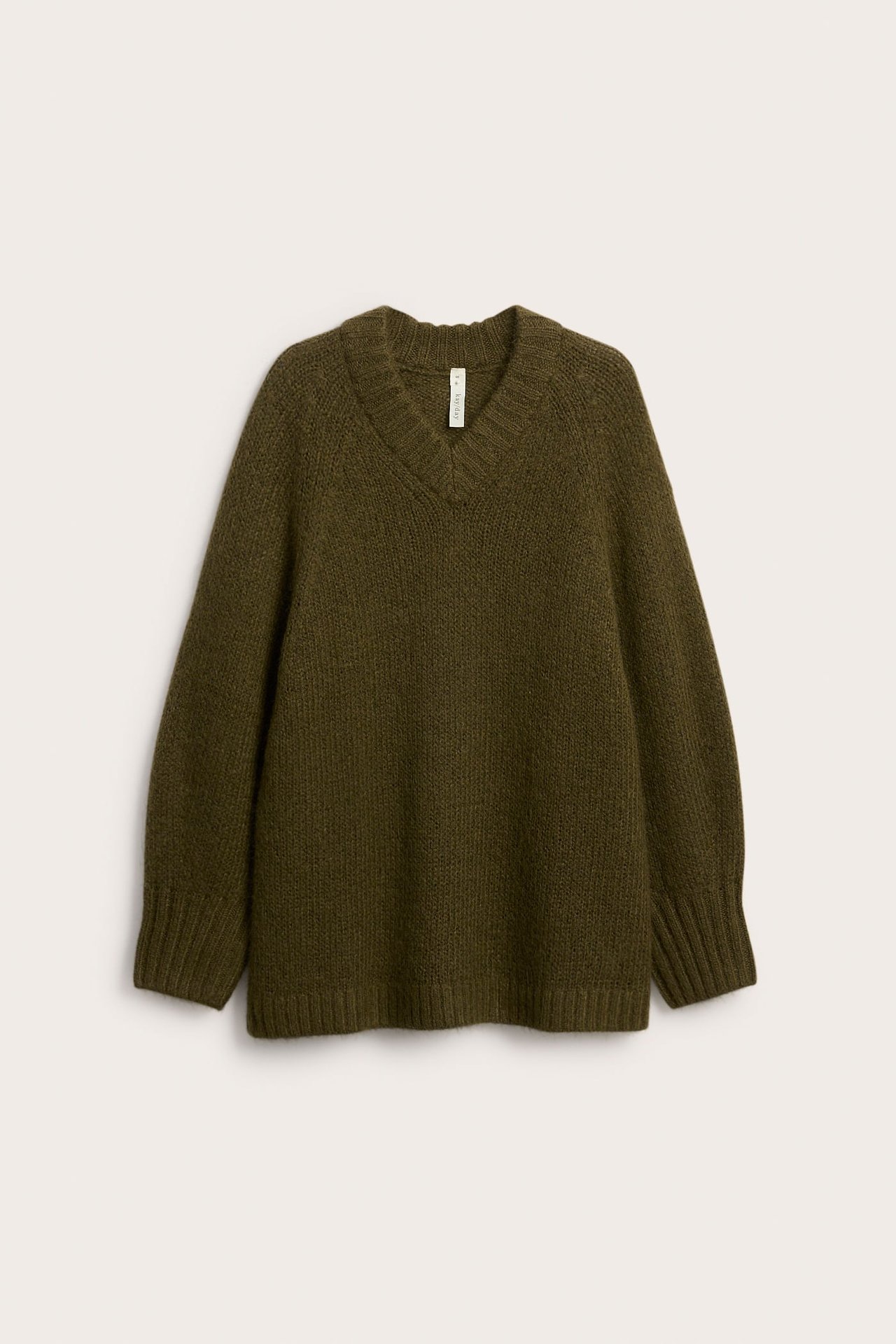 Edestäpäin kuvattu oversized vihreä villasekoiteneule V-pääntiellä ja raglanhihoilla.
