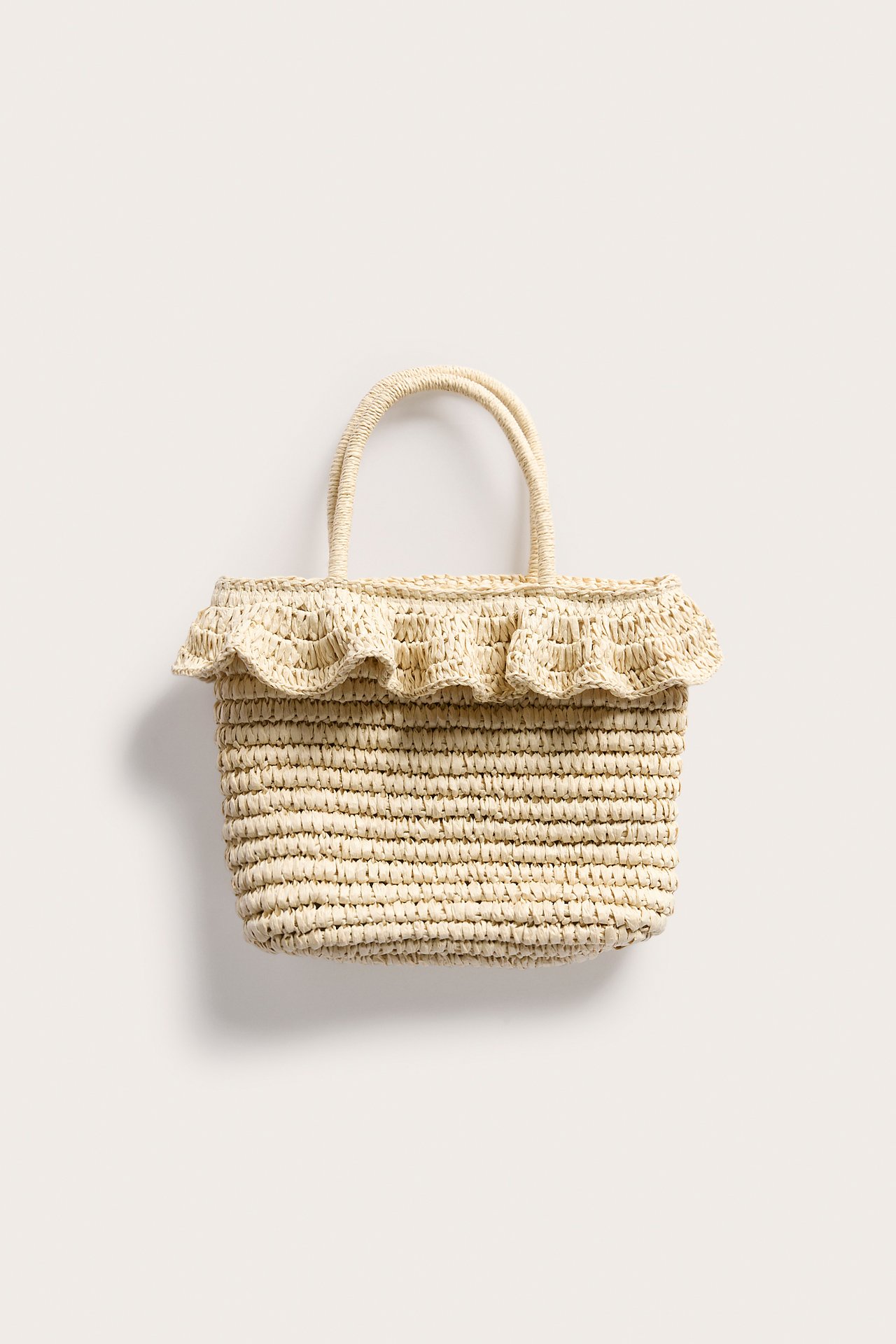 Widok z przodu beżowej torby ze słomy z dwoma uchwytami i falbanką u góry.