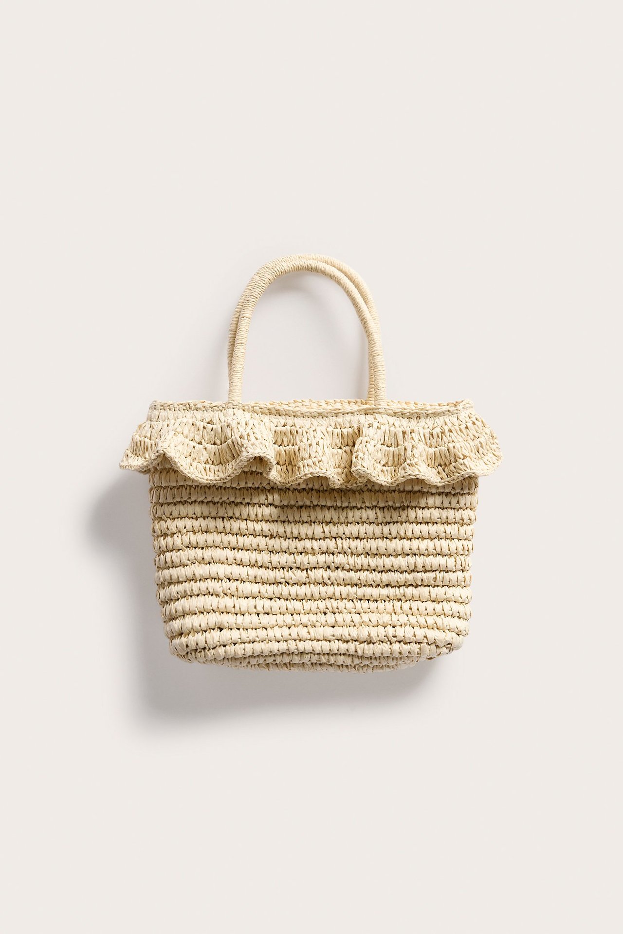 Edestä, vaaleanbeige olkilaukku kahdella kahvalla ja röyhelöreunalla ylhäällä.