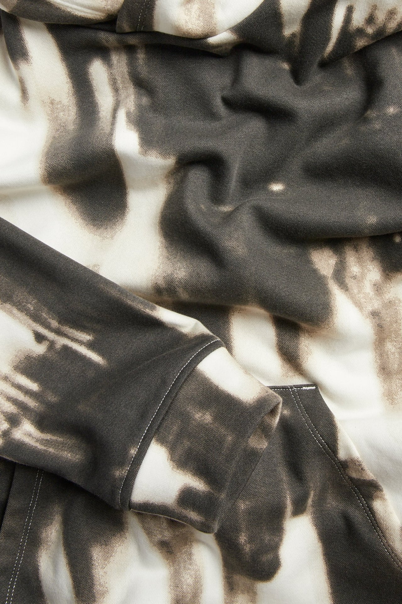 Zbliżenie na szarą i kremową bluzę z kapturem tie-dye.
