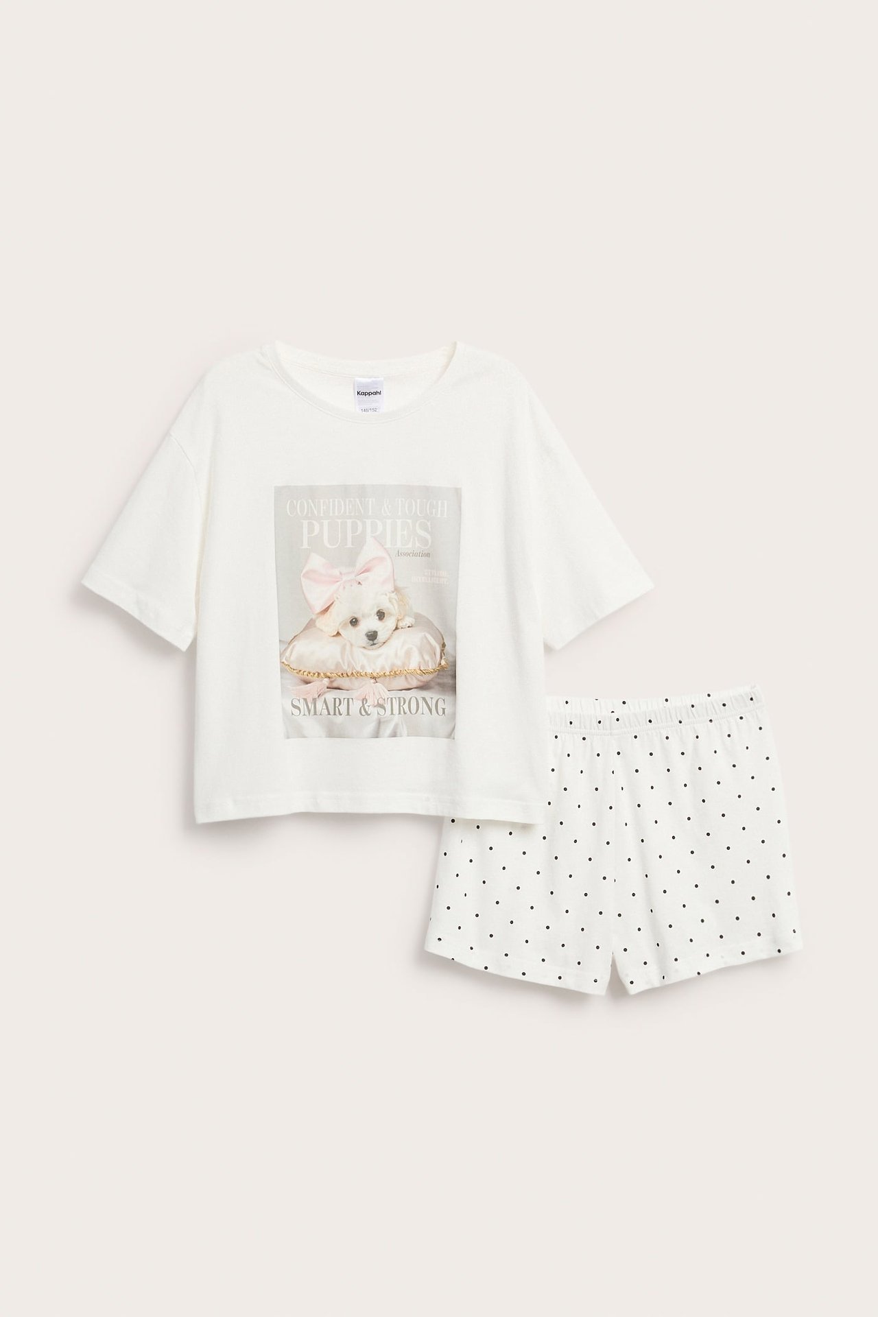 Edestäpäin: Luonnonvalkoinen puuvillainen lyhythihainen pyjama, jossa pentupainatus ja pilkulliset shortsit.