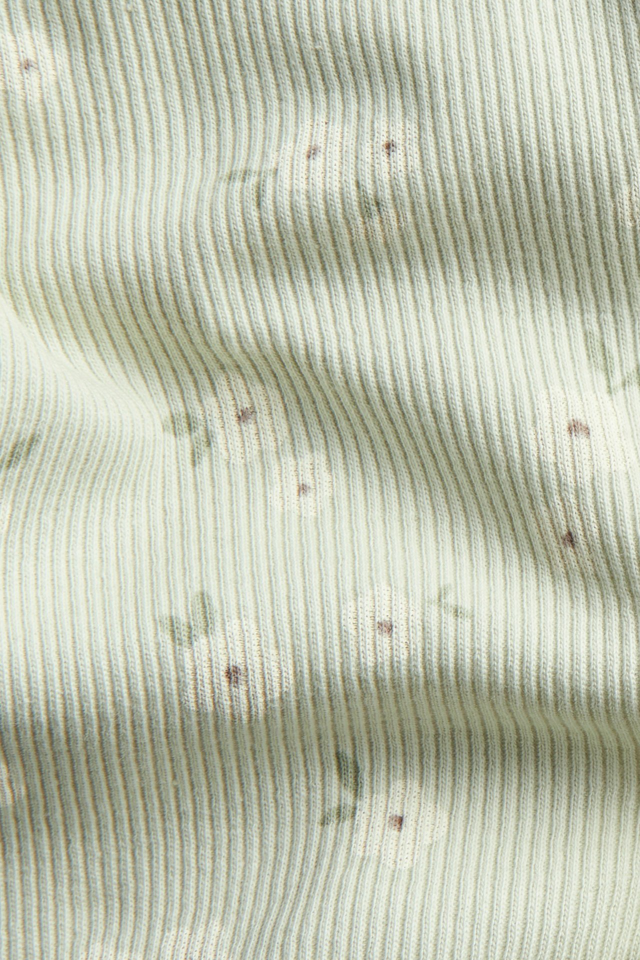 Nærbilde av lysegrønt ribbet bomullsblandingsstoff til leggings, med et diskret blomstermønster.