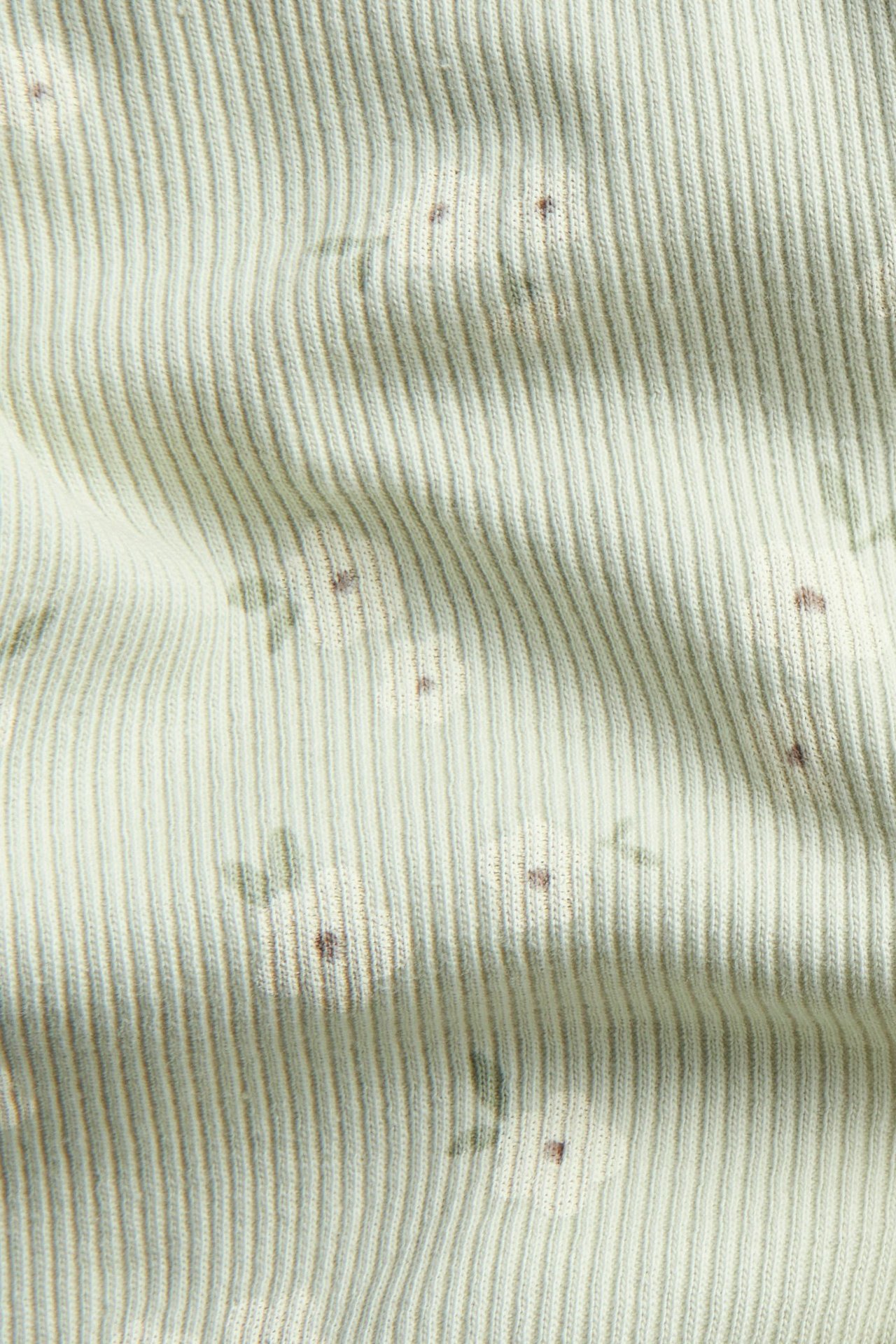 Närbild på ljusgrönt ribbat bomullstyg för leggings, med diskret blommigt heltryck.