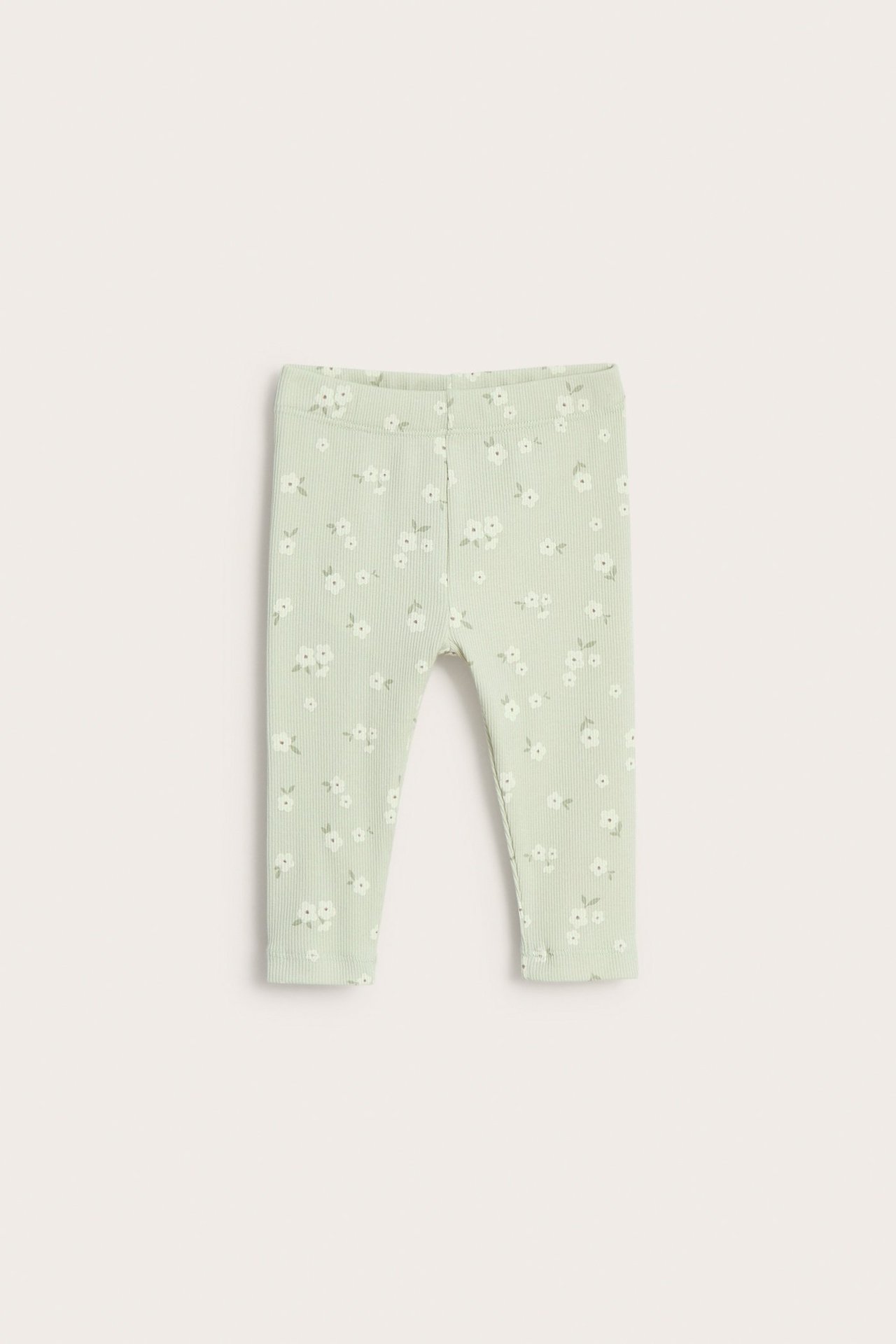 Framifrån: babyens ljusgröna ribbade leggings med ett litet vitt blommigt mönster.