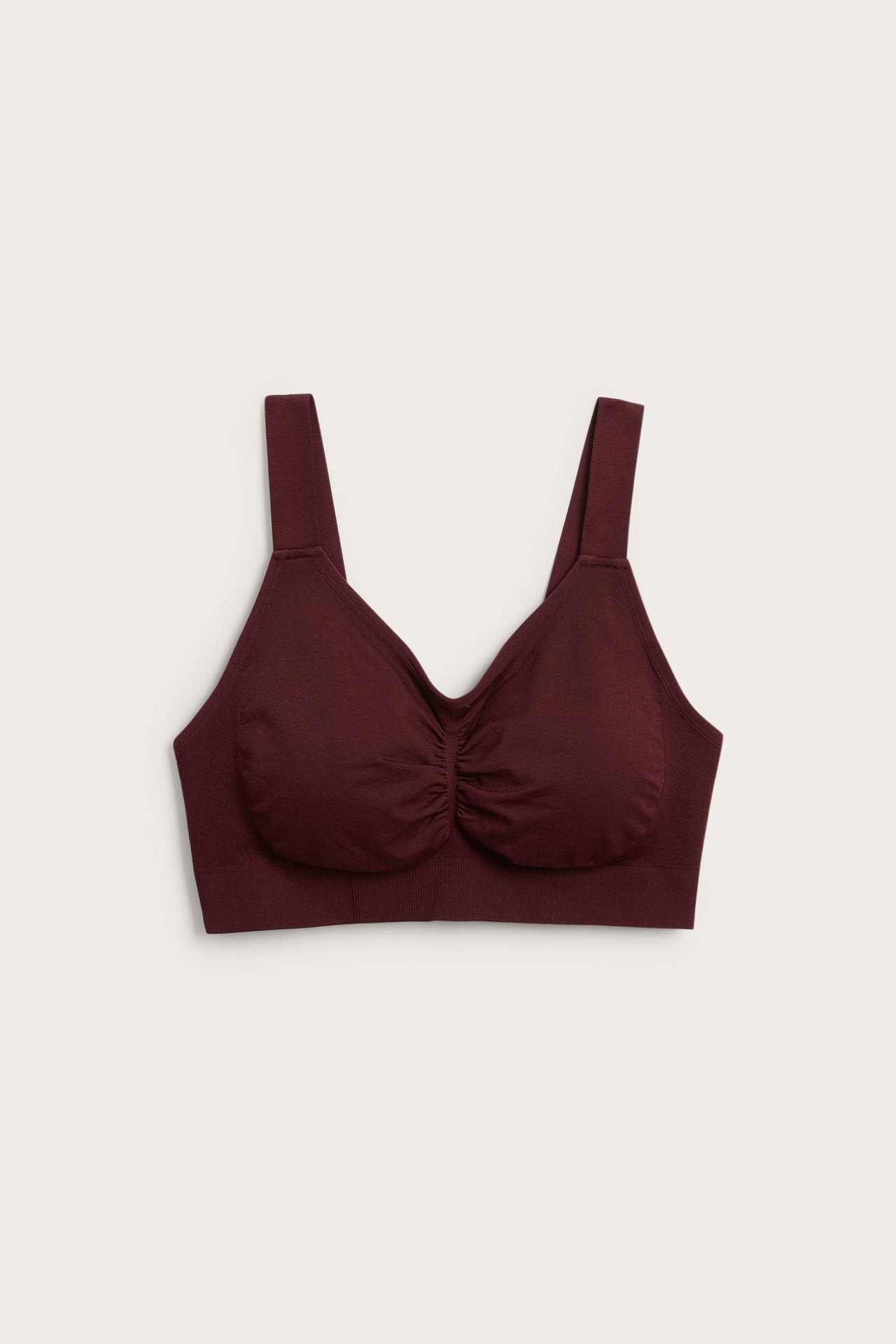 Widok z przodu bezszwowego bordowego biustonosza typu bralette z marszczeniem na środku.
