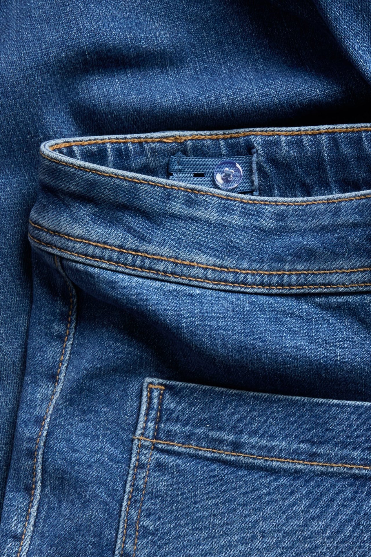 Lähikuva sinisistä farkuista säädettävällä vyötäröllä ja takataskulla.