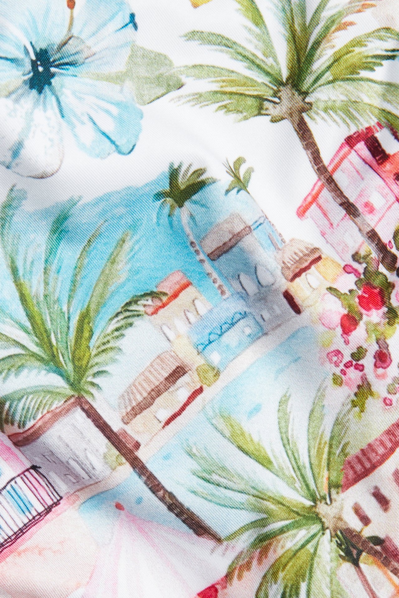 Zbliżenie na damski dół bikini z jasnozielonym tropikalnym wzorem palm i budynków.