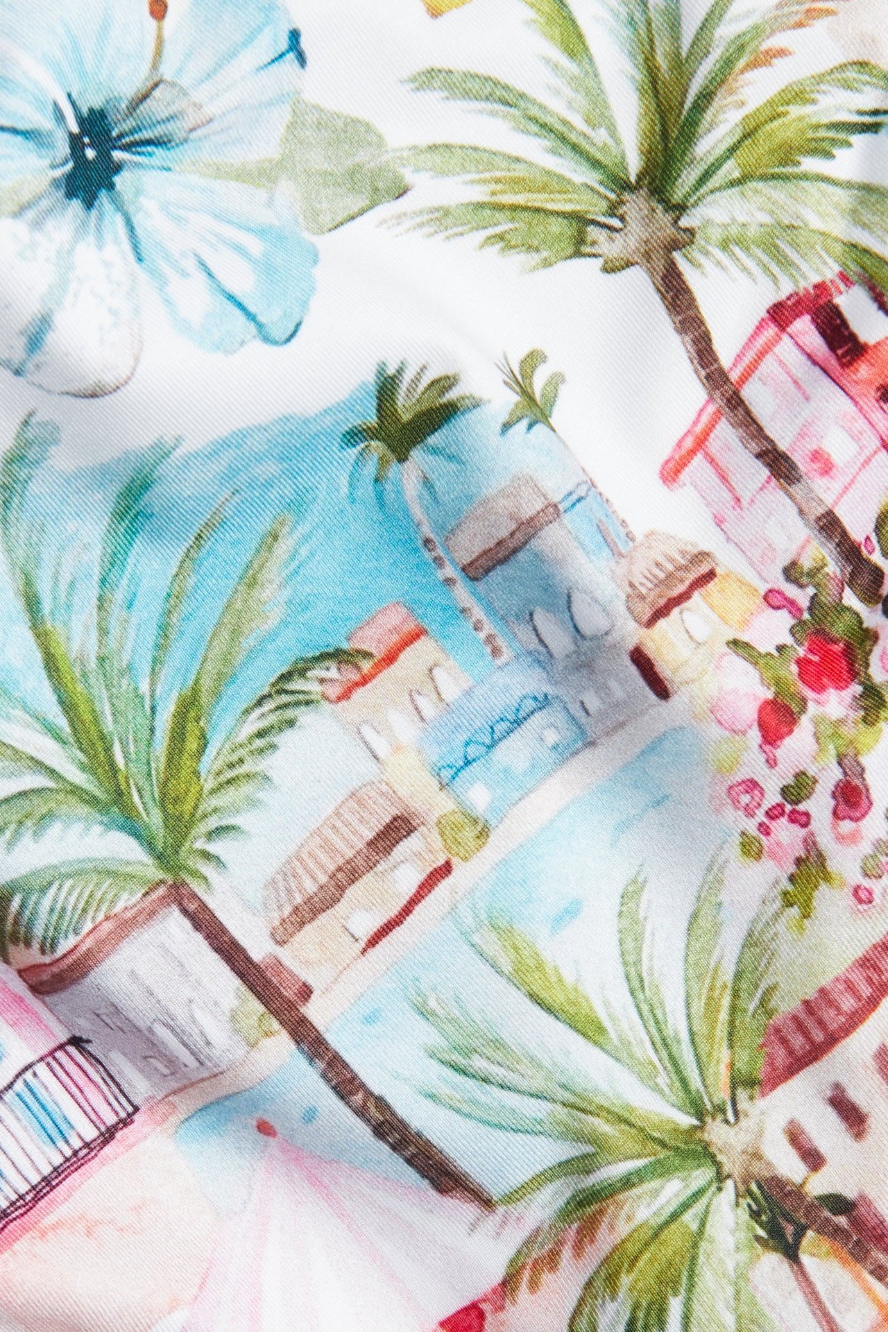 Zbliżenie na damski dół bikini z jasnozielonym tropikalnym wzorem palm i budynków.