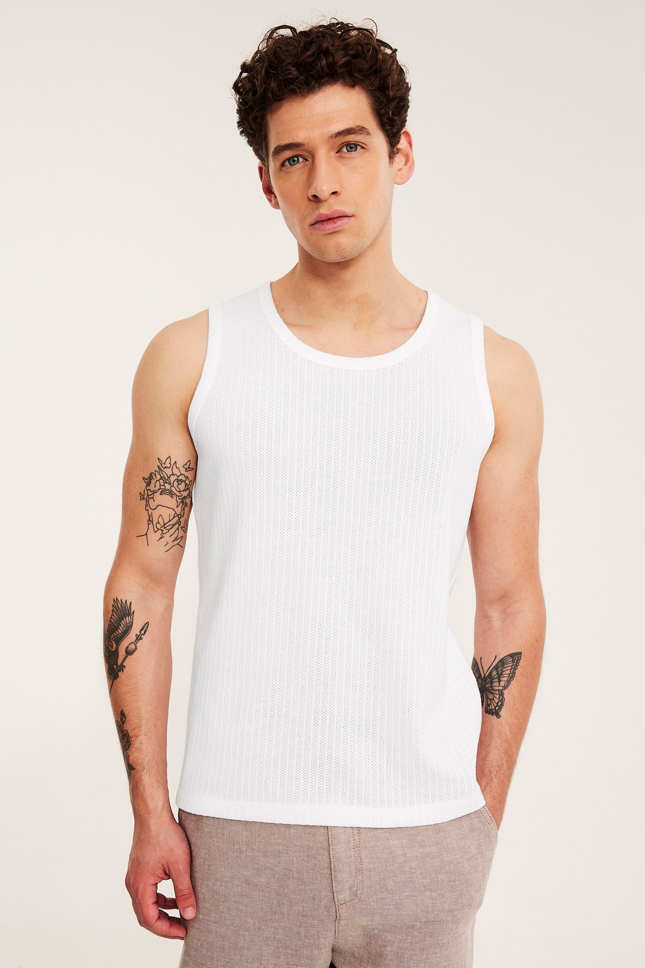 Framifrån: en man i vitt slim-fit pointelle linne och ljusbruna shorts.