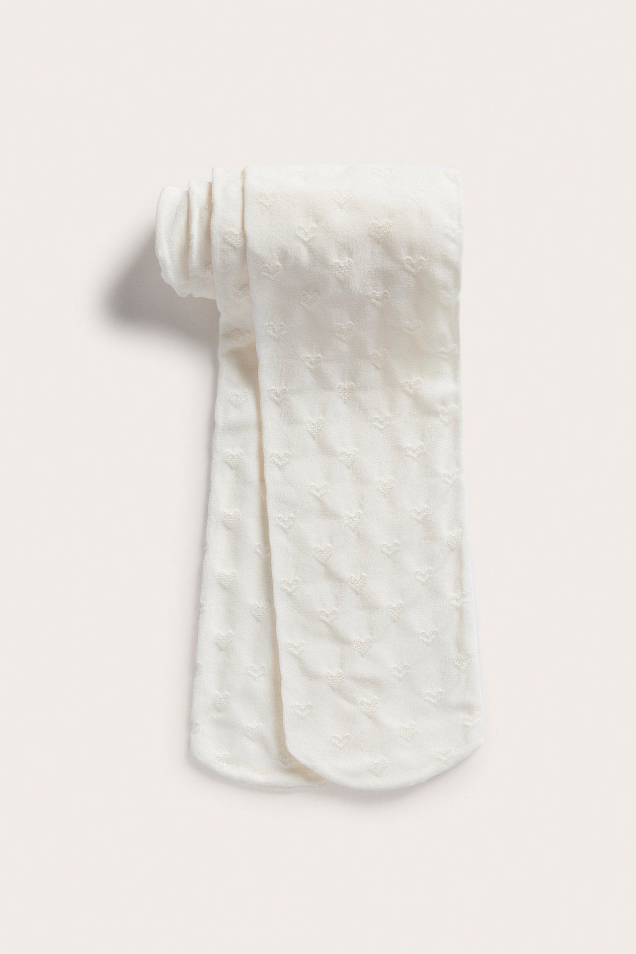 Tasokuva valkoisista lasten sukkahousuista, joissa on hienovarainen sydänkuvio.