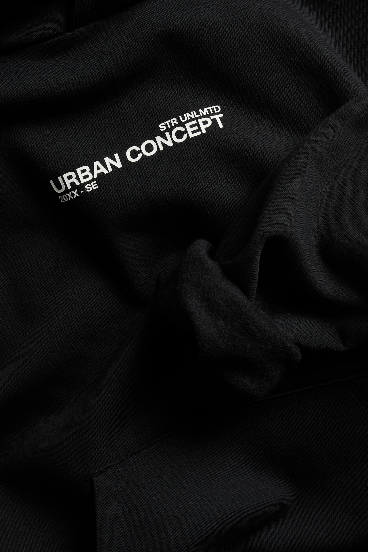 Lähikuva mustasta hupparista, jossa valkoinen "STR UNLMTD" ja "URBAN CONCEPT" -tekstipainatus.