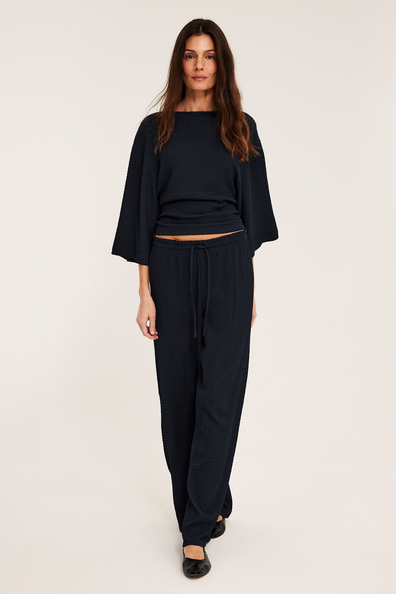 Frontvy: kvinna i mörkblå strukturerade jerseytbyxor med dragsko och en matchande topp.