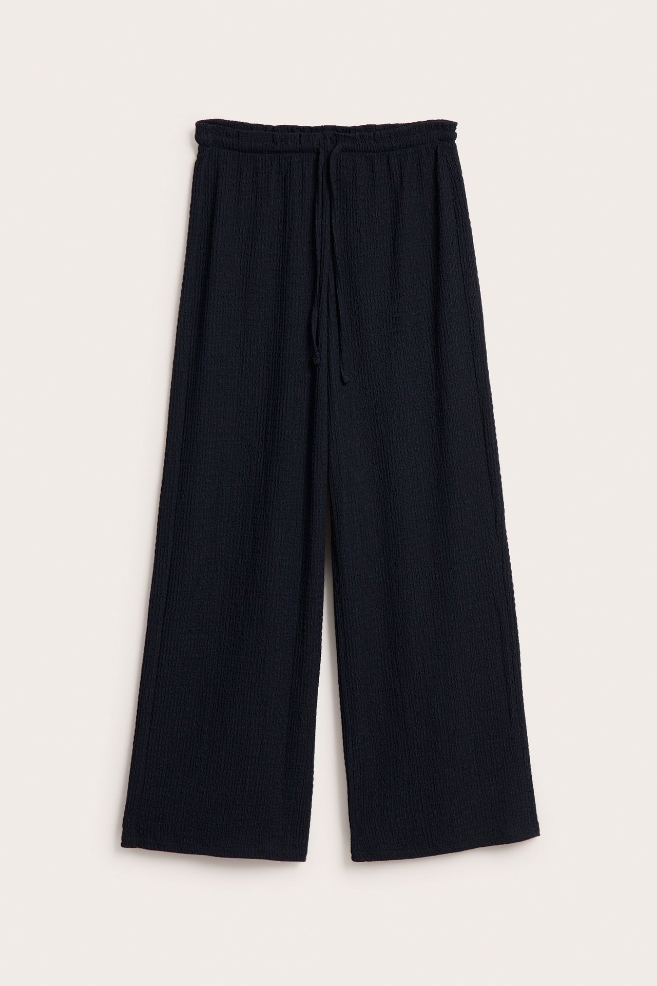Frontvy av mörkblå vida pull-on byxor i strukturerad jersey med dragsko i midjan.