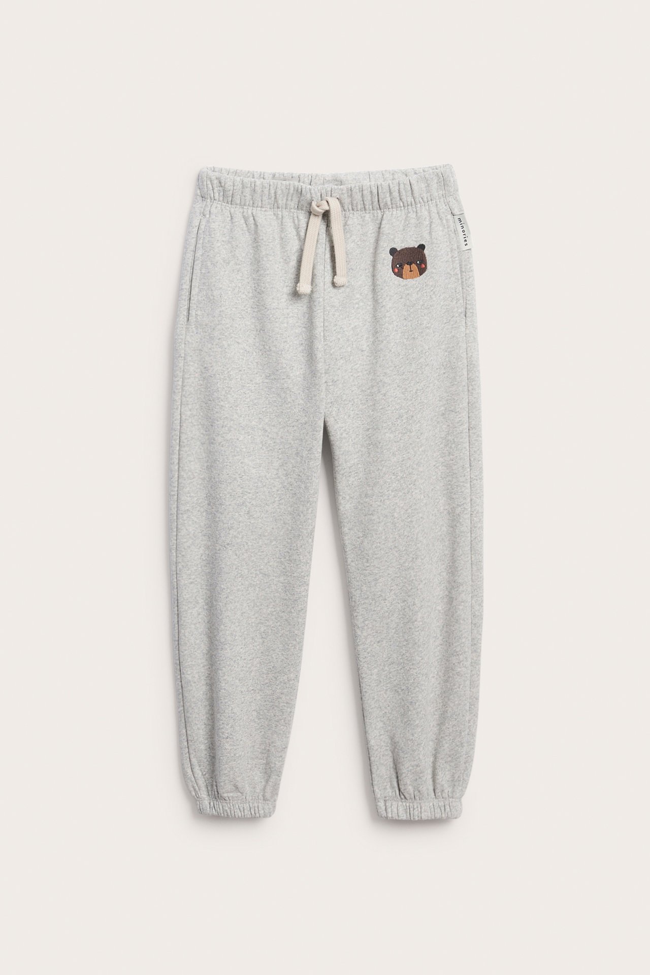 Front, gråmelert joggebukse til barn med bjørnebroderi og snøring i midjen.