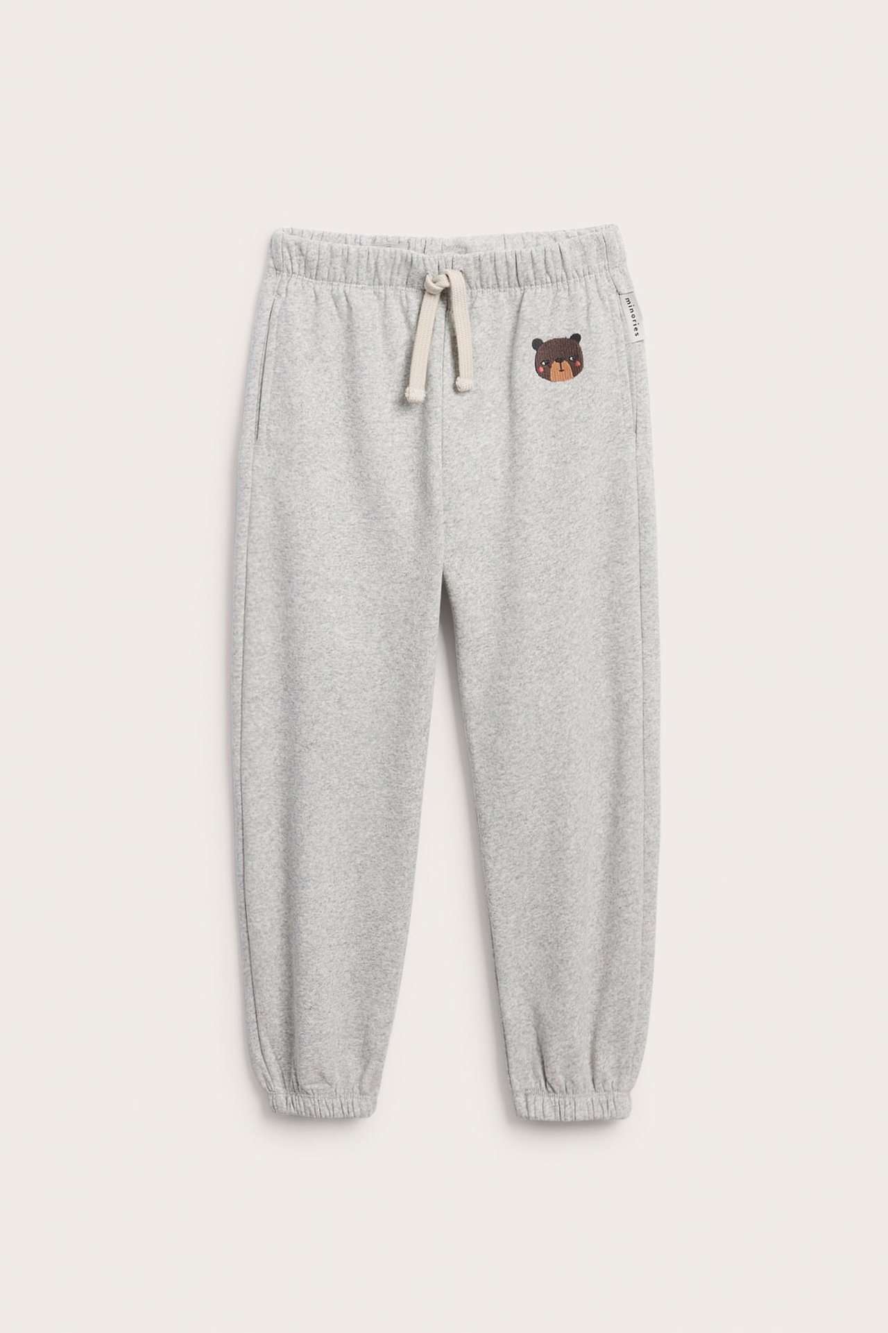 Front, gråmelert joggebukse til barn med bjørnebroderi og snøring i midjen.