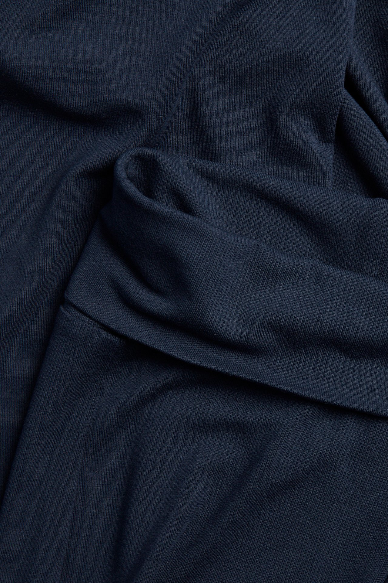 Lähikuva tummansinisistä levenevistä joogahousuista, joissa taitettava vyötärö, pehmeää trikookangasta.