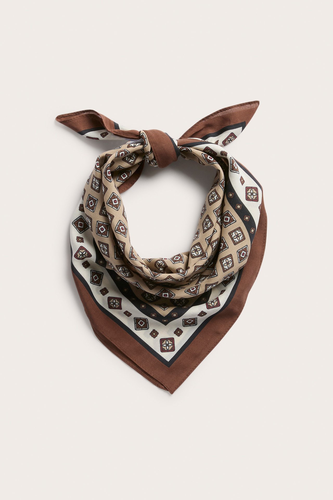 En plattbild av en brun, beige, krämvit och svart geometriskt mönstrad bandana knuten.