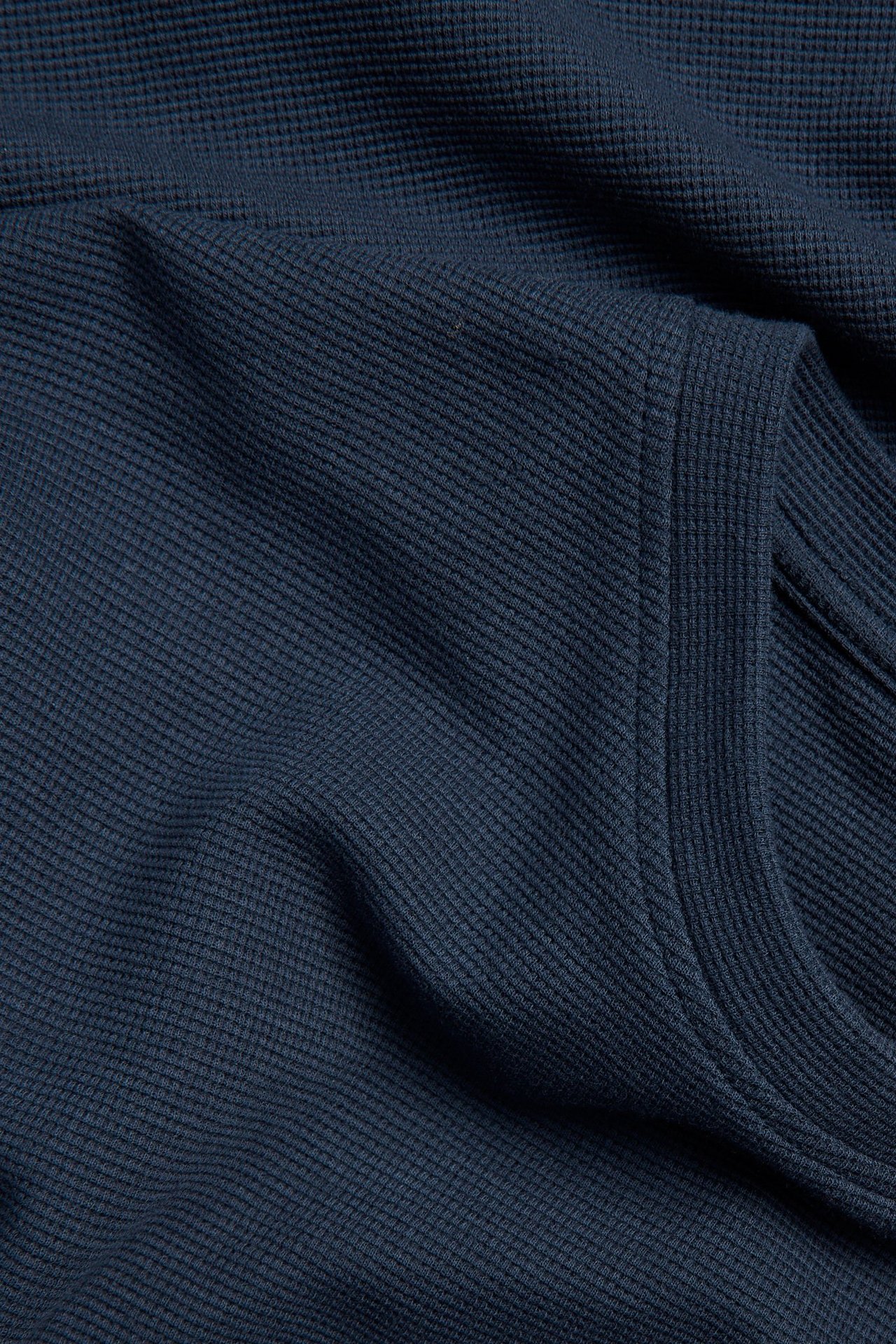 Lähikuva tummansinisestä miesten T-paidasta, jossa on kuviollinen pinta ja O-pääntie.