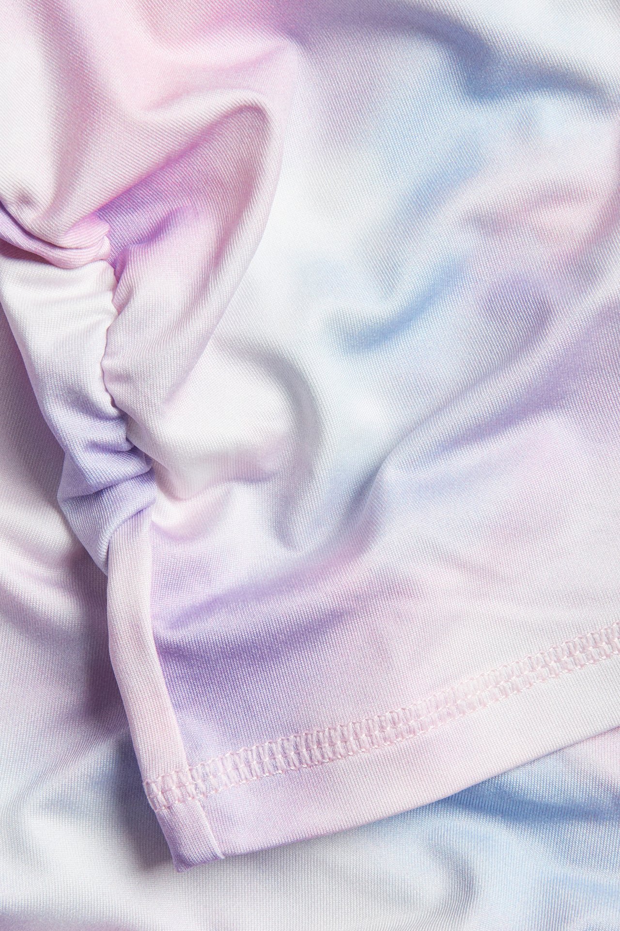 Lähikuva pastellinvärisestä, vaaleanpunaisesta, violetista, sinisestä ja valkoisesta tie-dye-urheilutopista, jossa on rypytettyjä yksityiskohtia.