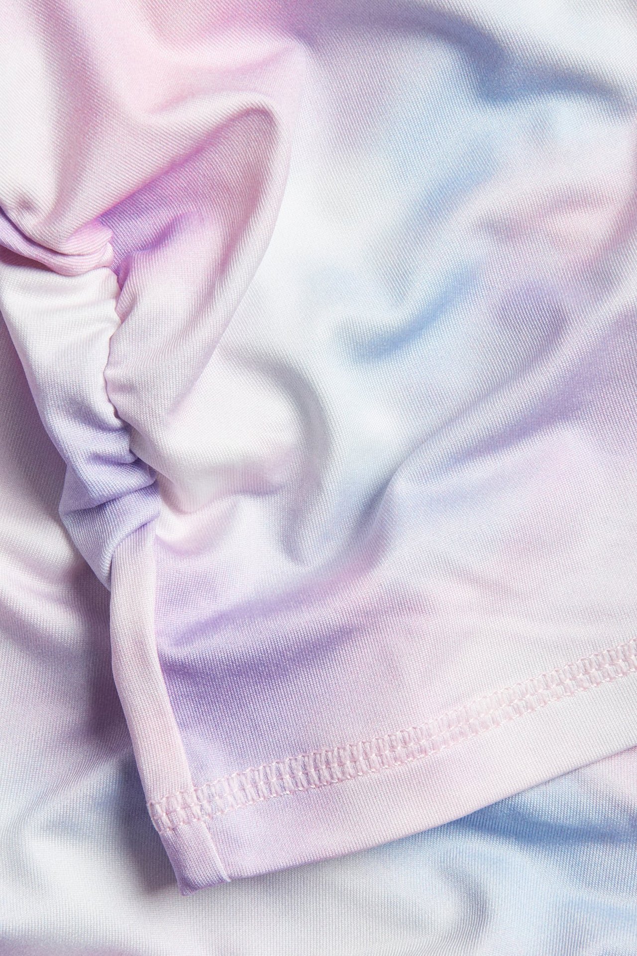 Zbliżenie na pastelowy różowo-fioletowo-niebiesko-biały top treningowy tie-dye z marszczonymi detalami.