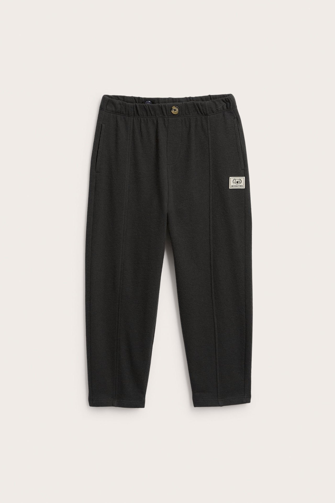 Svart joggebukse forfra med elastisk midje, knapp, sidelommer og benlapp.