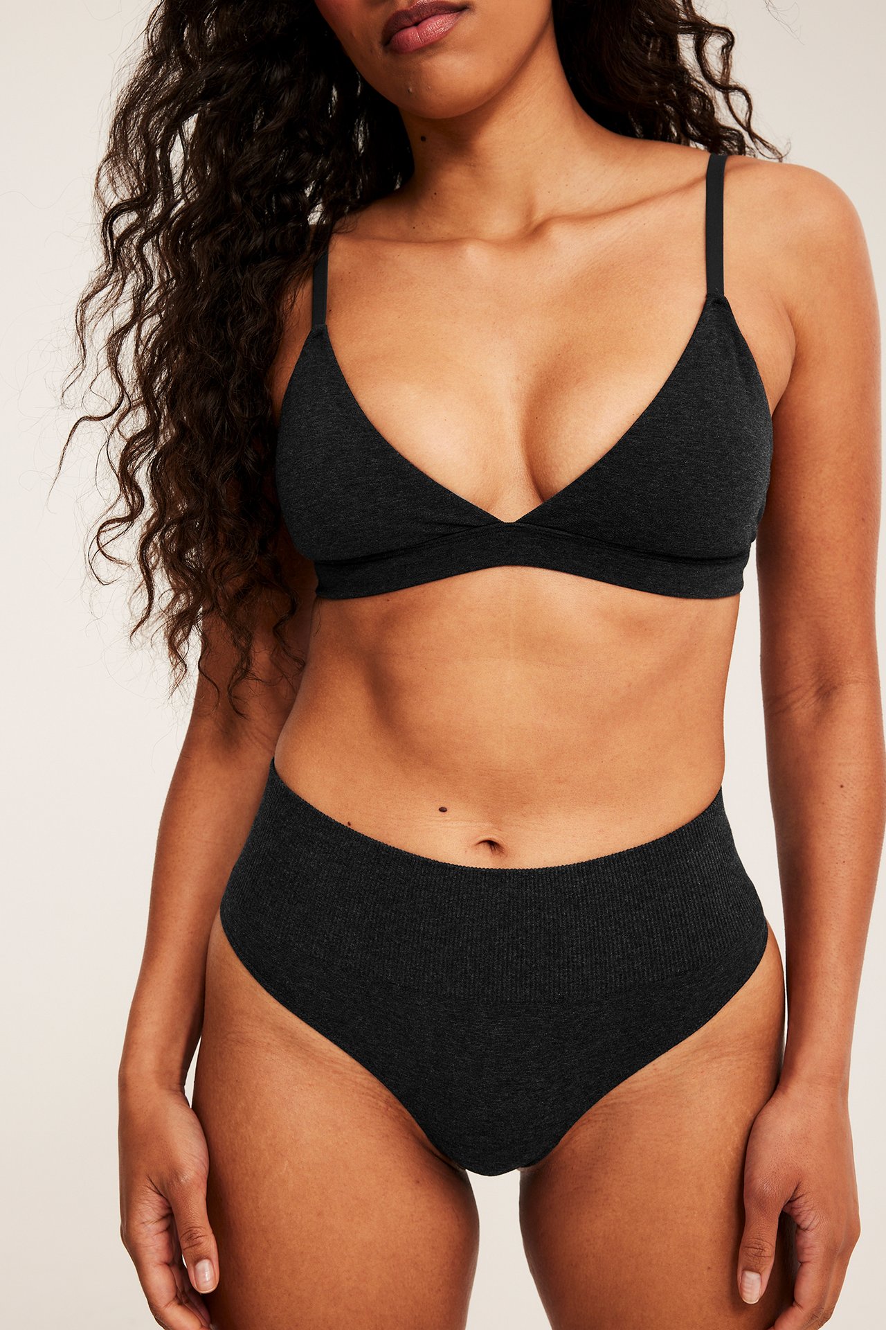 Frontbilde av kvinnelig modell iført mørkegrå ribbet bralette med matchende høy midje truse.