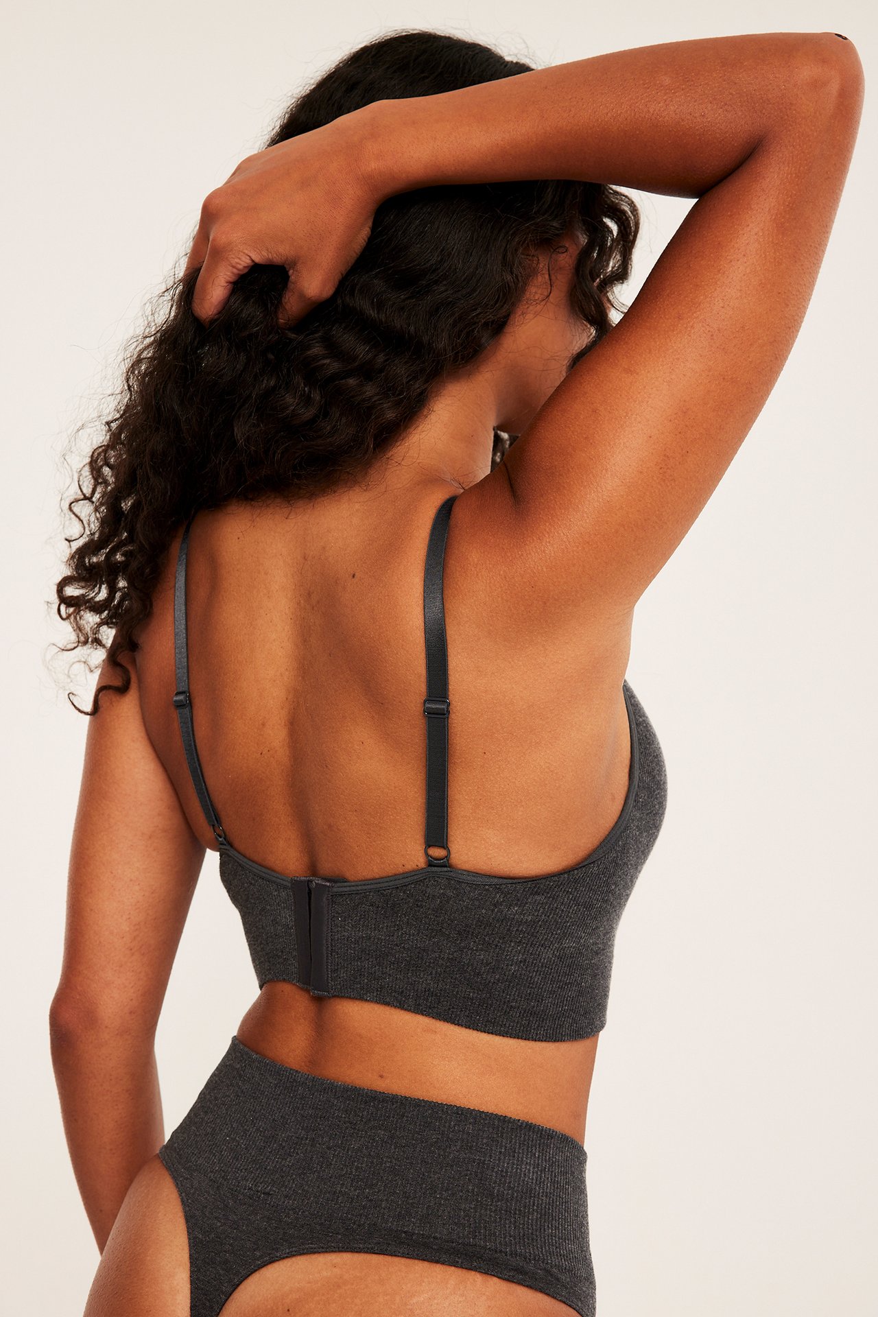 Baksidan av en kvinna i en mörkgrå ribbad bralette och matchande högmidjade trosor.