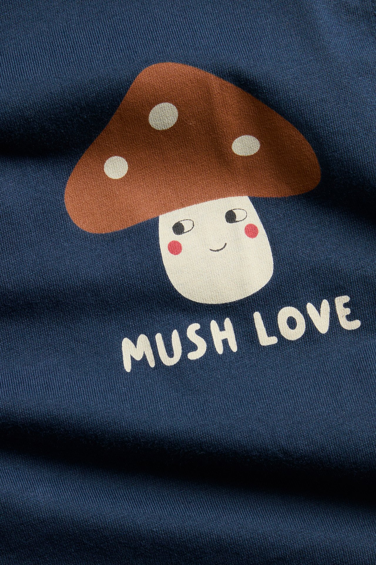 Zbliżenie ciemnoniebieskiej bluzki z uśmiechniętą grafiką grzyba i napisem 'MUSH LOVE'.